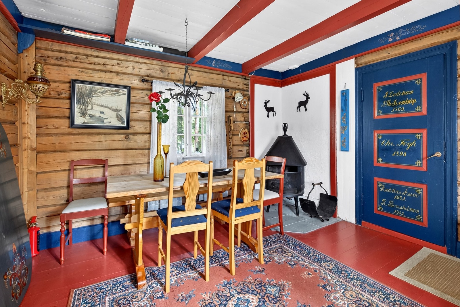 Spiseplass med vedovn for kalde kvelder. Legg merke til den blåmalte døren som dokumenterer eiendommens eierhistorikk helt tilbake til 1869 - en unik detalj! Galleribilde