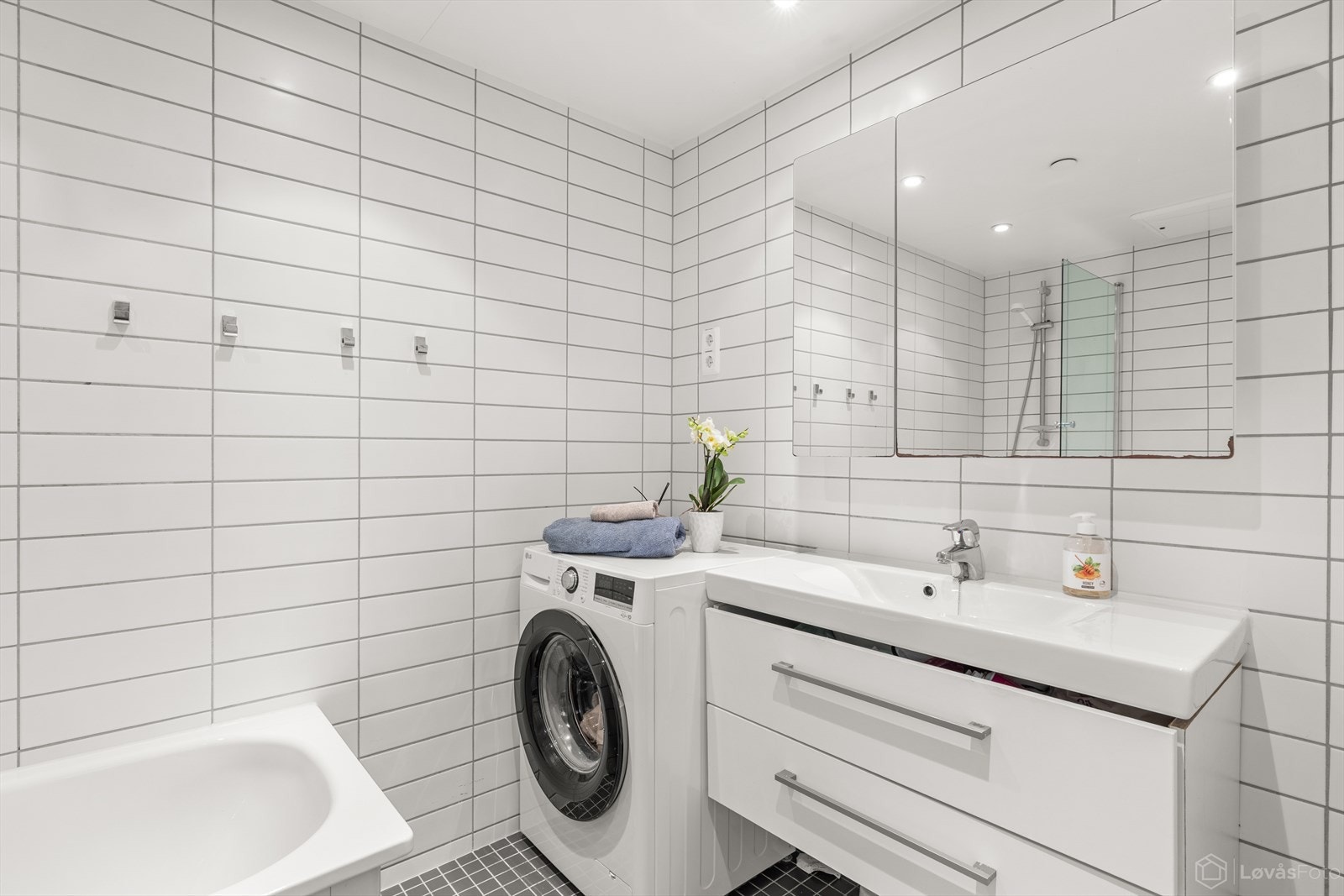Badet har opplegg for vaskemaskin og er utstyrt med servant med innredning, vegghengt toalett og badekar. Galleribilde