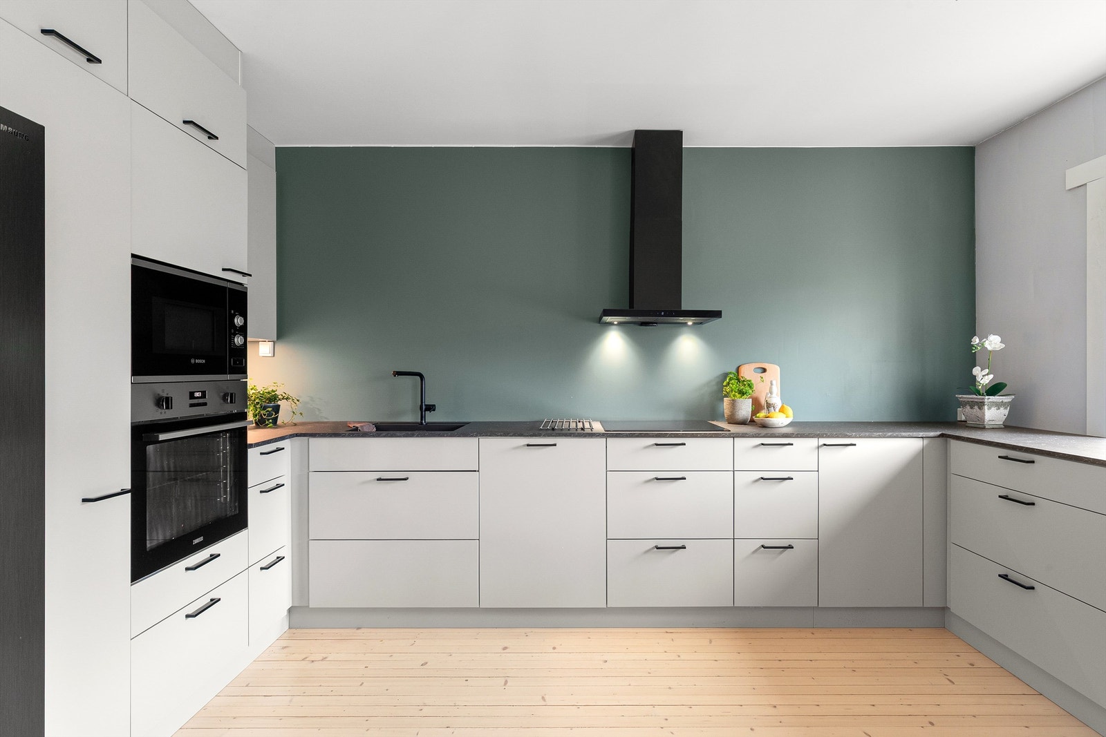 Moderne og tidløst kjøkken fra Kvik med en praktisk og stilren benkeplate av laminat, induksjonstopp, fritthengende ventilator med kullfilter og overskapsbelysning. Galleribilde
