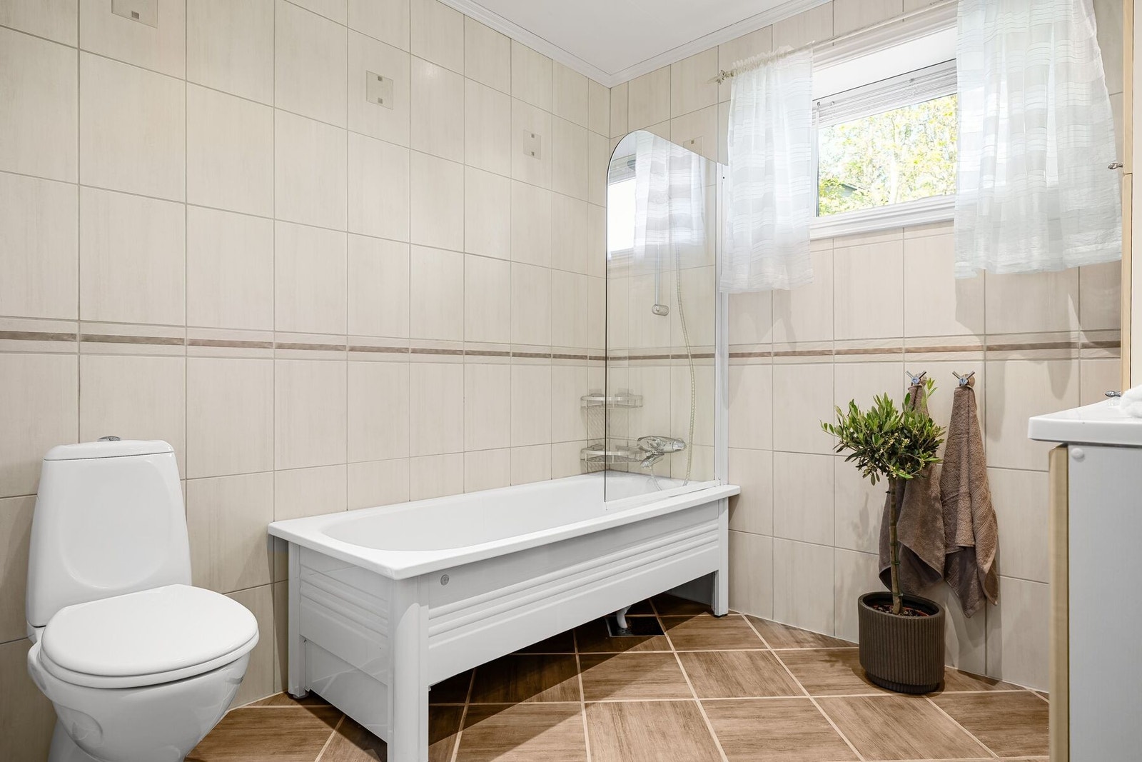 Badet er utstyrt med baderomsinnredning, badekar og toalett Galleribilde
