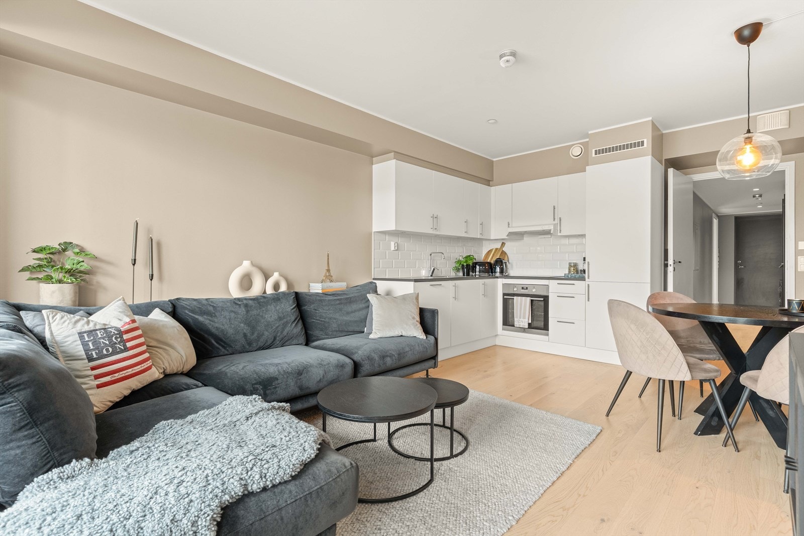Stuen fremstår moderne og lettmøblert, med plass til både sofagruppe og spisebord. Den åpne løsningen skaper en luftig romfølelse og gjør leiligheten svært sosial. Galleribilde