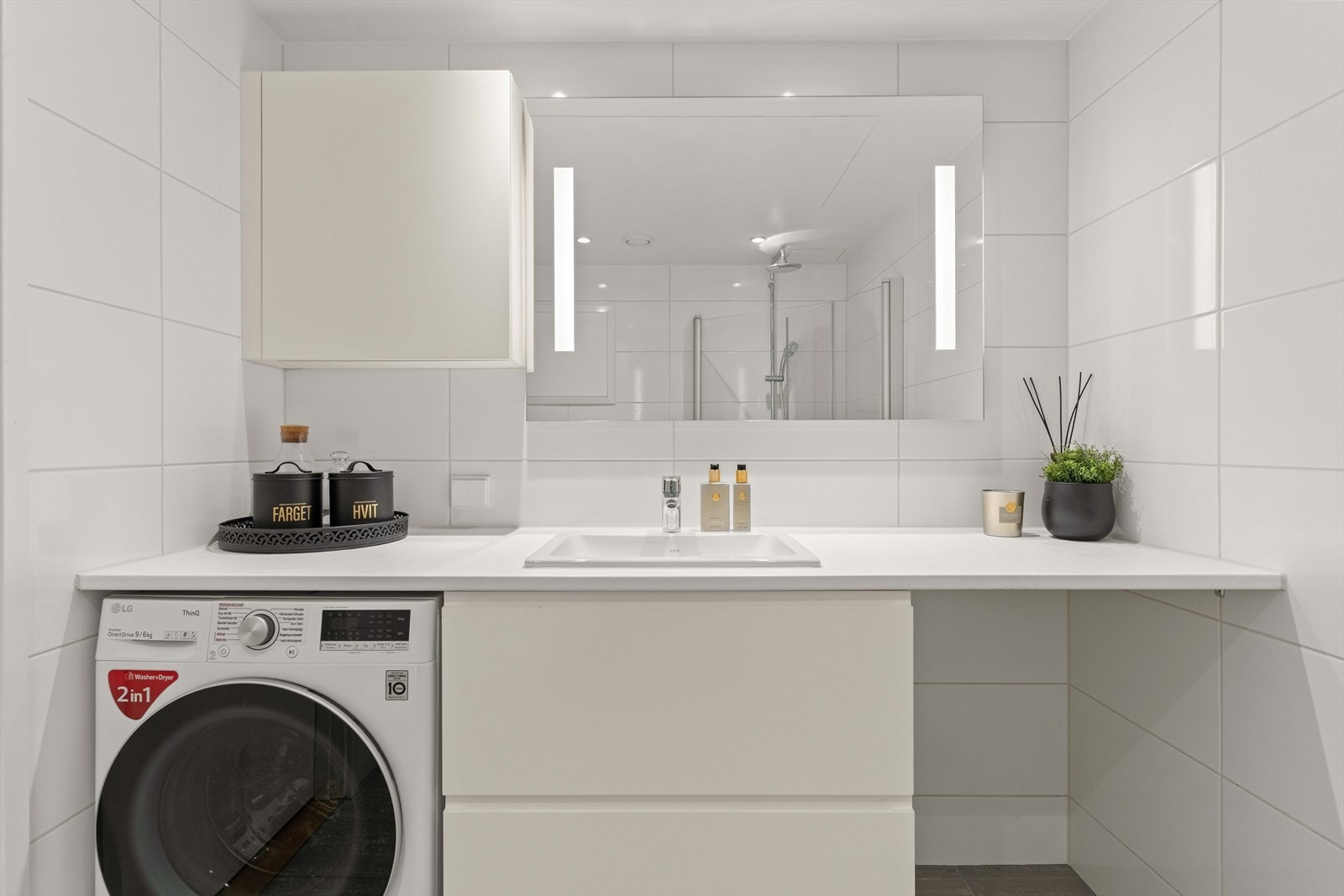 Badet har stilren innredning med god benke- og skapplass. Speil med belysning og lyse flater gir rommet et rent og moderne uttrykk. Galleribilde