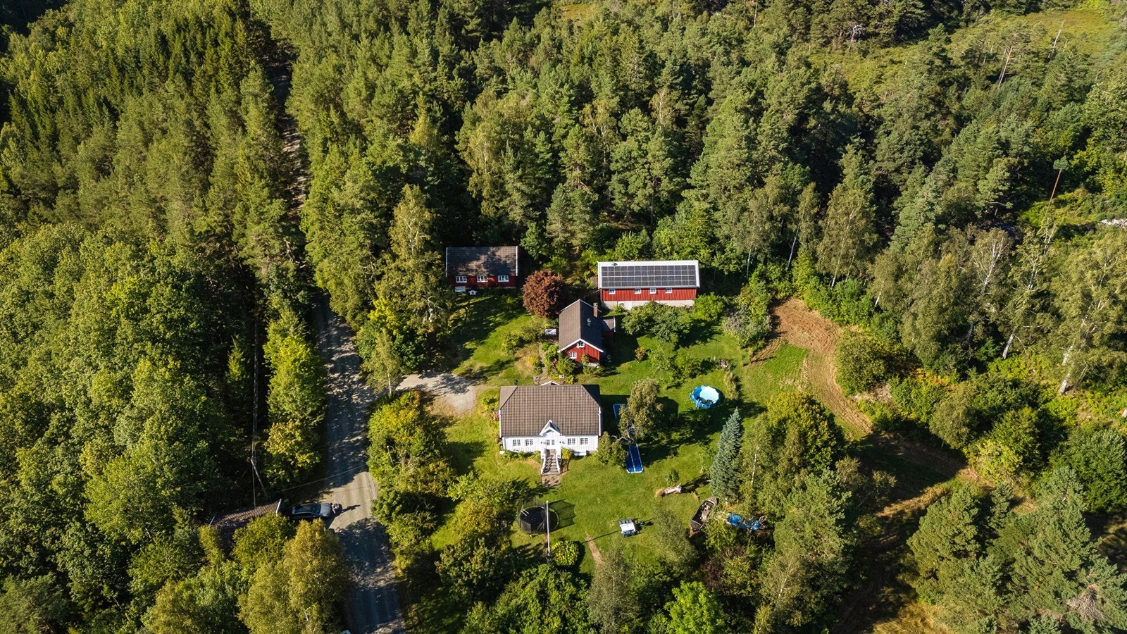 Oversikten over byggningene på eiendommen. Dobbel garasje til venstre. Hoppbakken bak garasjen. Galleribilde