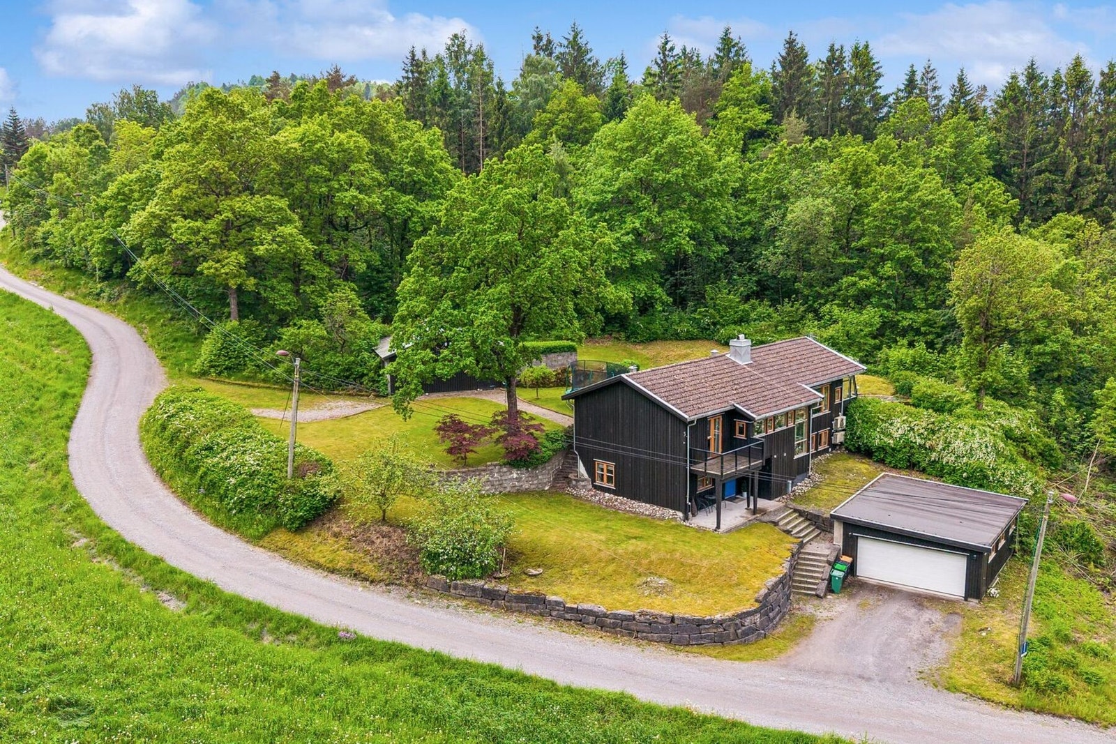 Dronebilde av eiendommen. Legg merke til parkeringen ved garasjen og på stikkvei inn til bod/garasje. Galleribilde