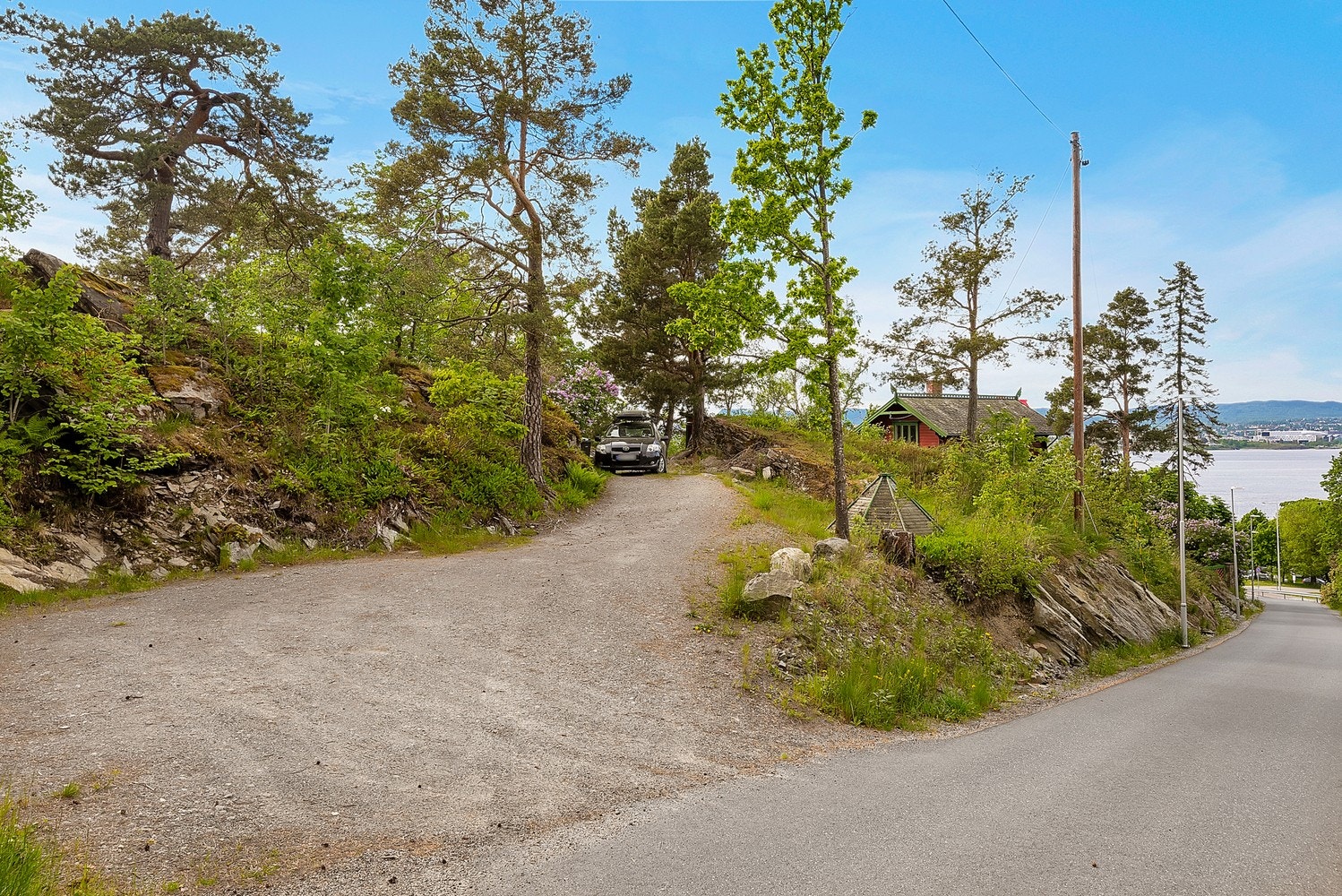 Adkomst fra den øverste eiendommen gbnr. 4/29 som er avsatt til bolig i reguleringsplanen. Brukes i dag til innkjøring og parkeringsplass for 5-6 biler. Galleribilde