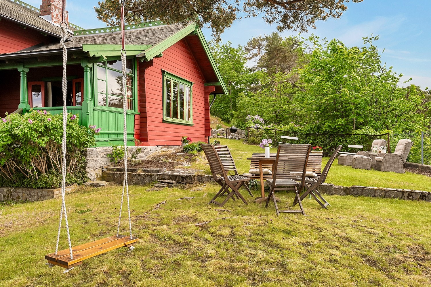 Tomten er opparbeidet med plen, steinheller og prydbusker. Galleribilde