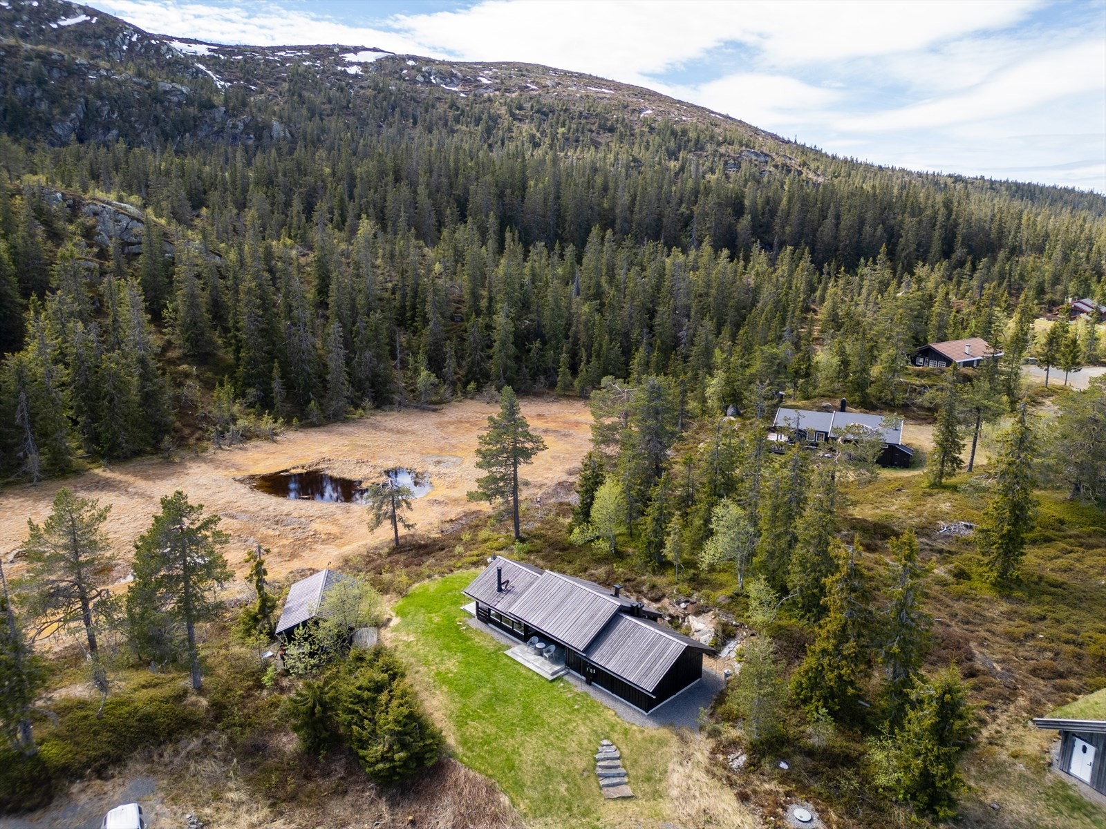 Hytta ligger usjenert til i skrånende terreng, med fjell og skog som nærmeste nabo. Galleribilde