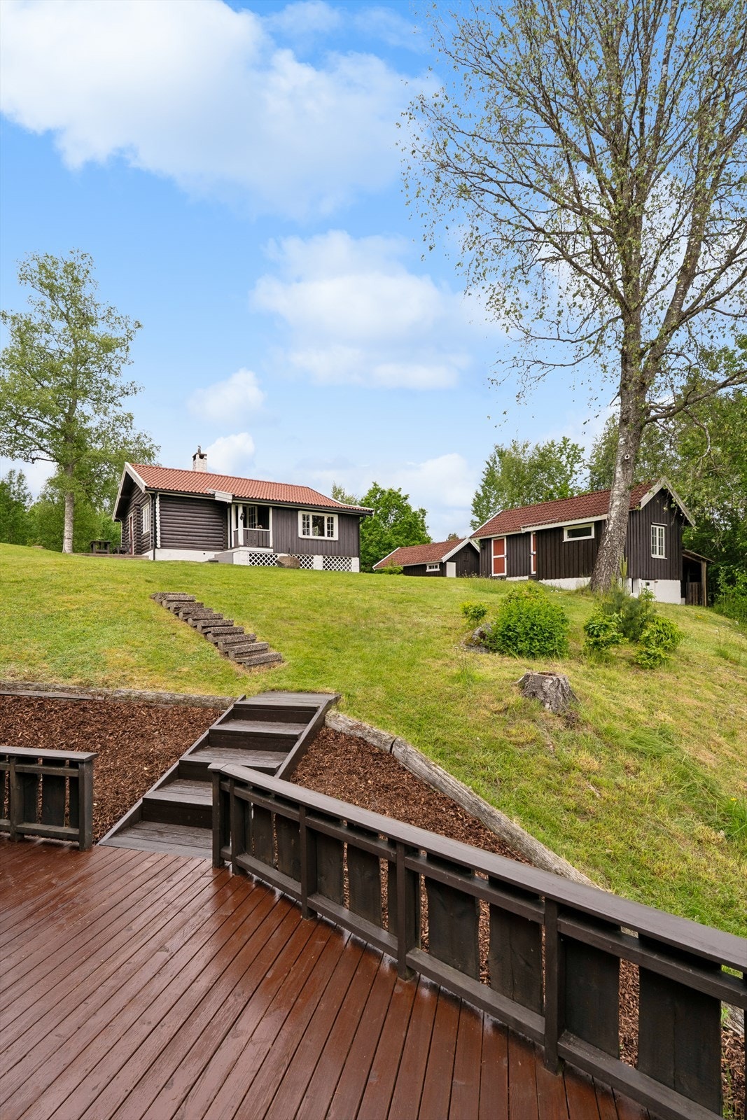 Tomten skråner lett ned mot vannet, med trapper som forbinder de ulike nivåene. Galleribilde
