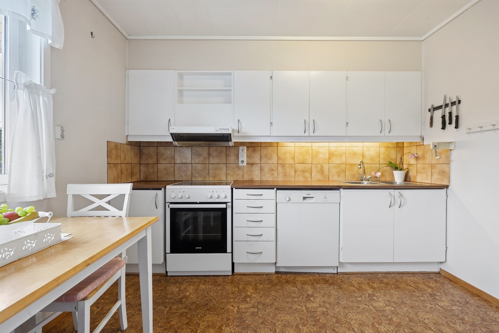 Kjøkkeninnredning med slette fronter og godt med skap- og benkeplass. Kjøkkenventilator og opplegg for oppvaskmaskin. Galleribilde