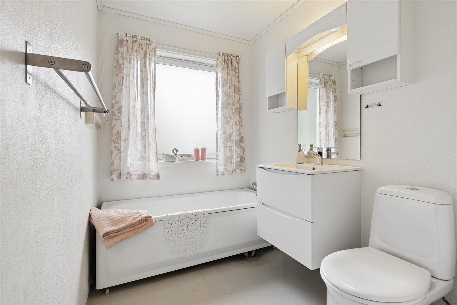 Badet i 1. etasje er fra byggeåret og innehar servantinnredning fra 2026, overskap, speil m/belysning over, badekar og toalett. Galleribilde