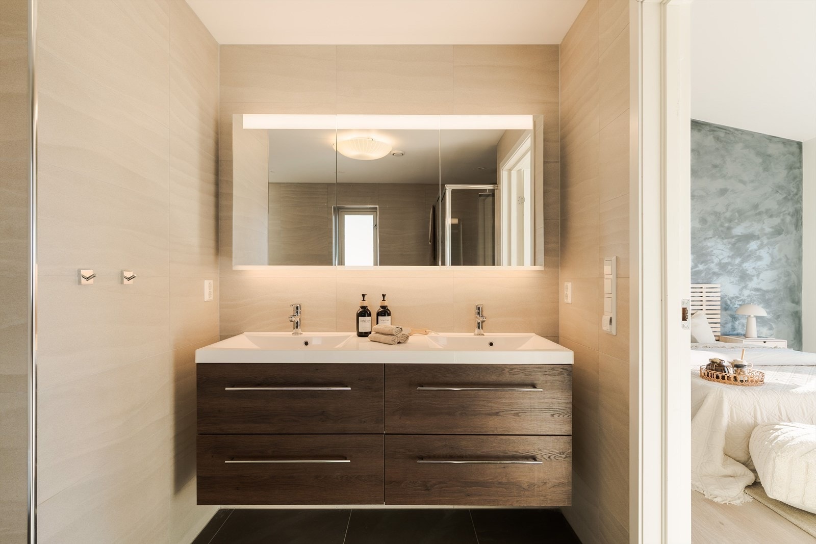 Badet er romslig og moderne, og ligger i tilknytning til hovedsoverommet. Rommet er belagt med lyse fliser på veggene og mørke gulvfliser. Galleribilde