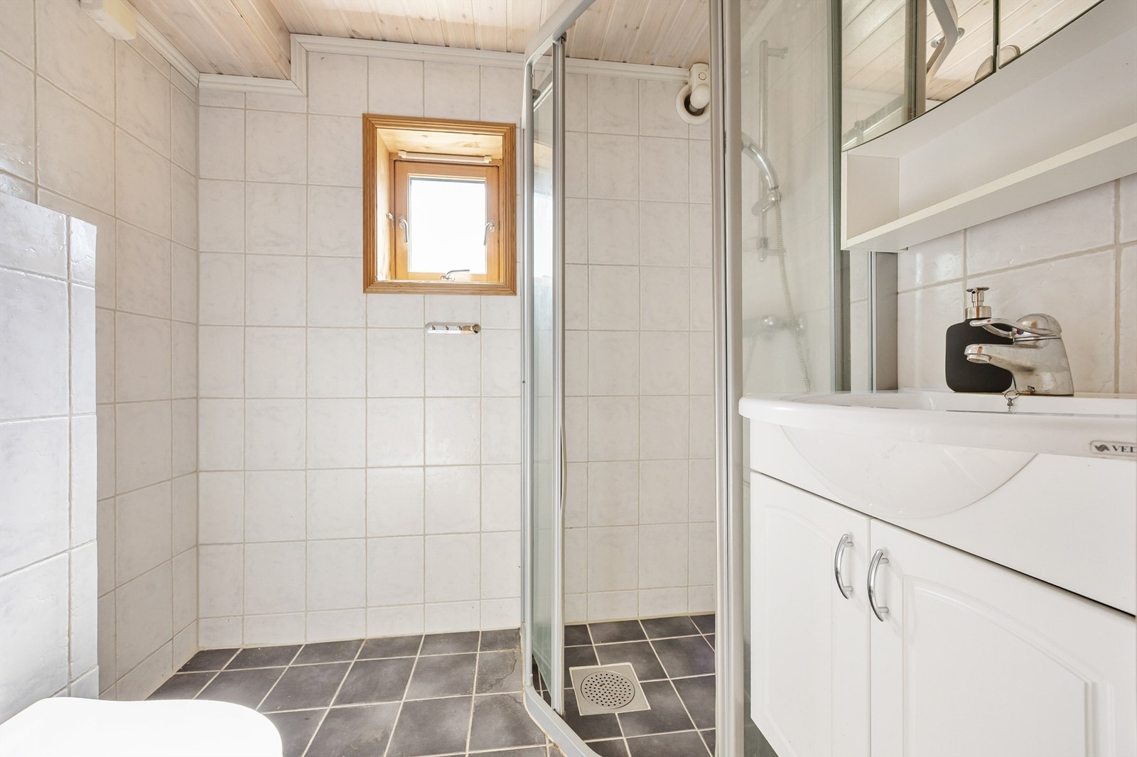 Badet i underetasjen er flislagt og utstyrt med dusj, servant og opplegg for vaskemaskin. Galleribilde