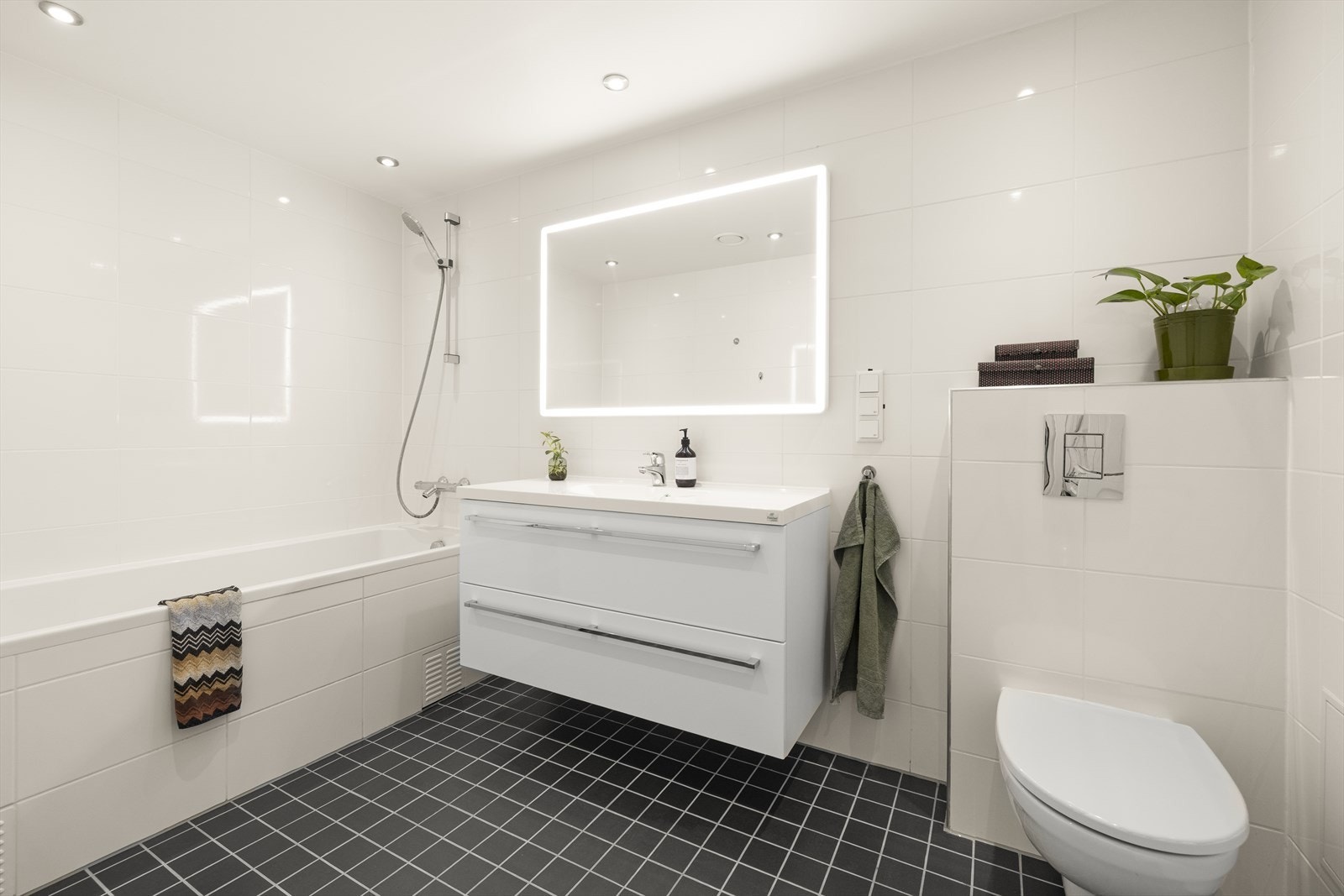 Badet i underetasjen er moderne utført med flislagte gulv og vegger, og inneholder badekar, vegghengt toalett og servantinnredning. Galleribilde