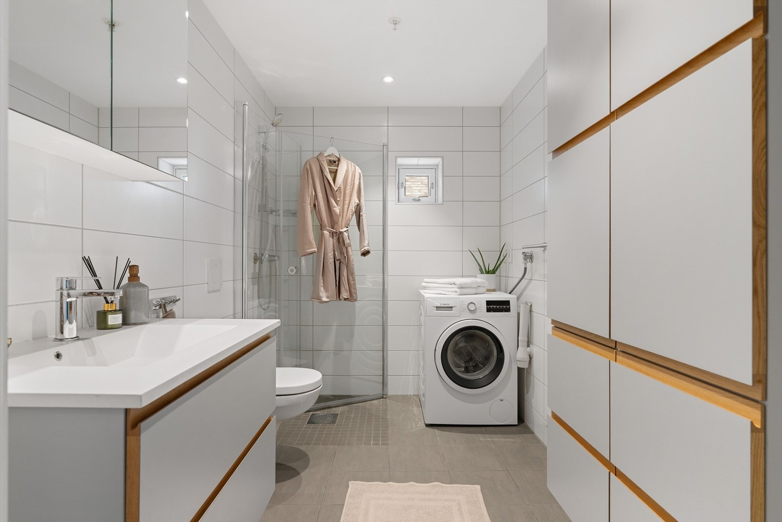 Badet har flislagte overflater, downlights og gulvvarme. Samme innredning som på kjøkkenet går igjen på badet. Galleribilde