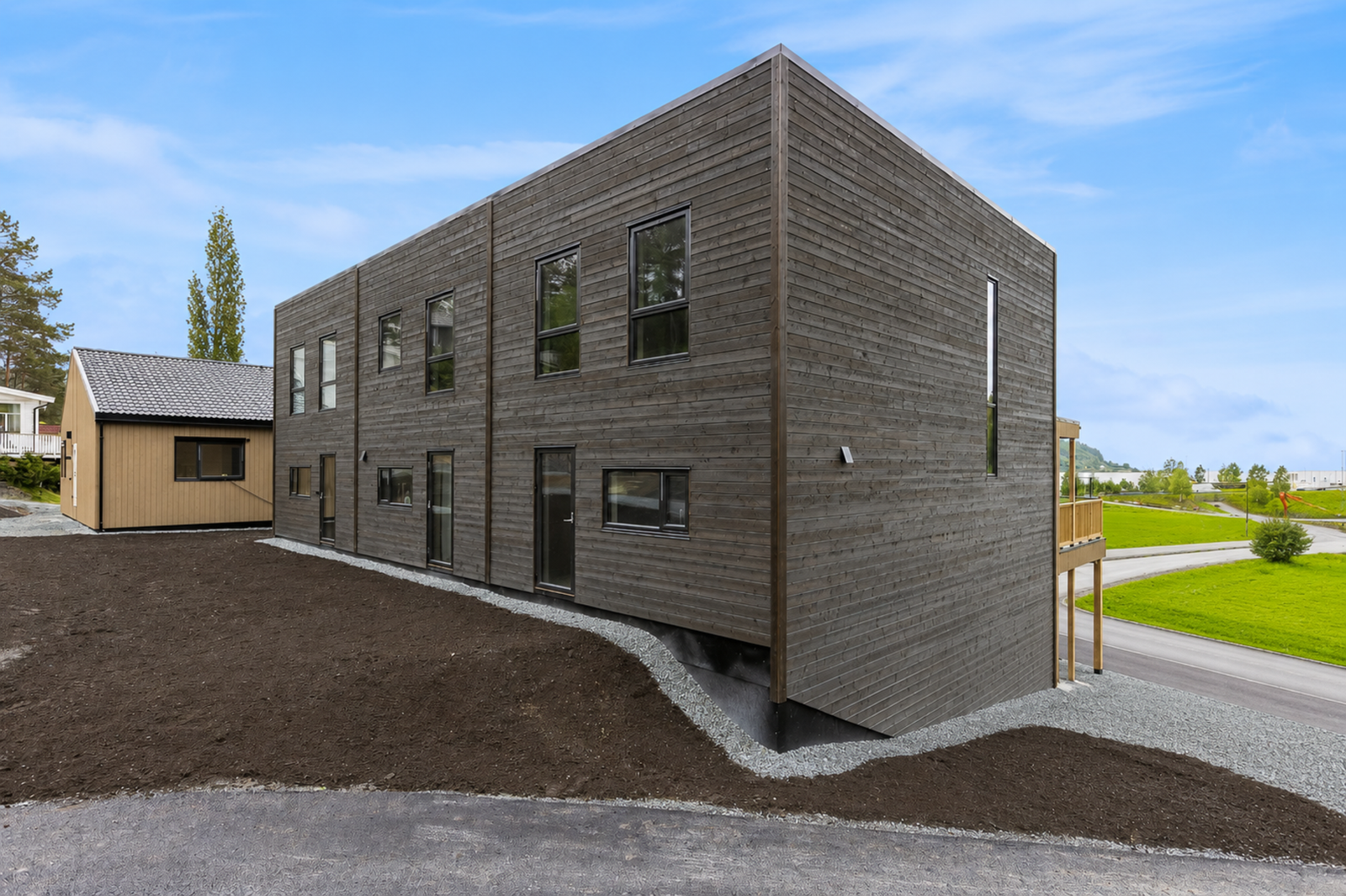 Fasade av boligen. Det gjøres oppmerksom på at uteområde er redigert med AI. det er noen avvik i terrenget på siden av boligen. Galleribilde