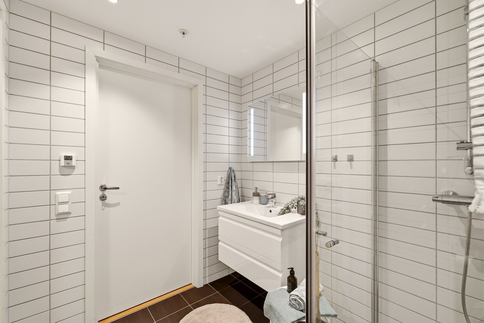 Badet har vegghengt toalett, servantinnredning og dusj med glassdører. Galleribilde