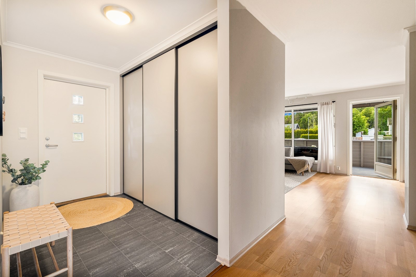 Langs veggen er det montert en stor skyvedørsgarderobe som byr på rikelig med oppbevaringsplass til yttertøy, sko og annet utstyr. Skyvedørene utnytter plassen effektivt og bidrar til et ryddig og stilrent uttrykk. Galleribilde