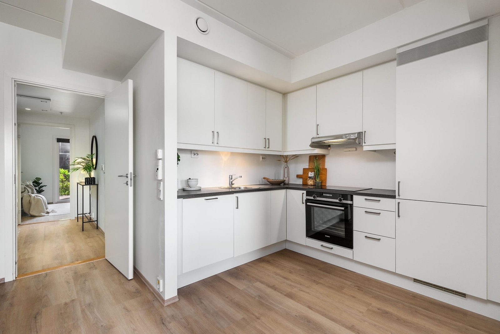 Moderne kjøkkeninnredning med hvite, glatte fronter. Laminat benkeplate med rett frontkant. Integrerte hvitevarer. Galleribilde