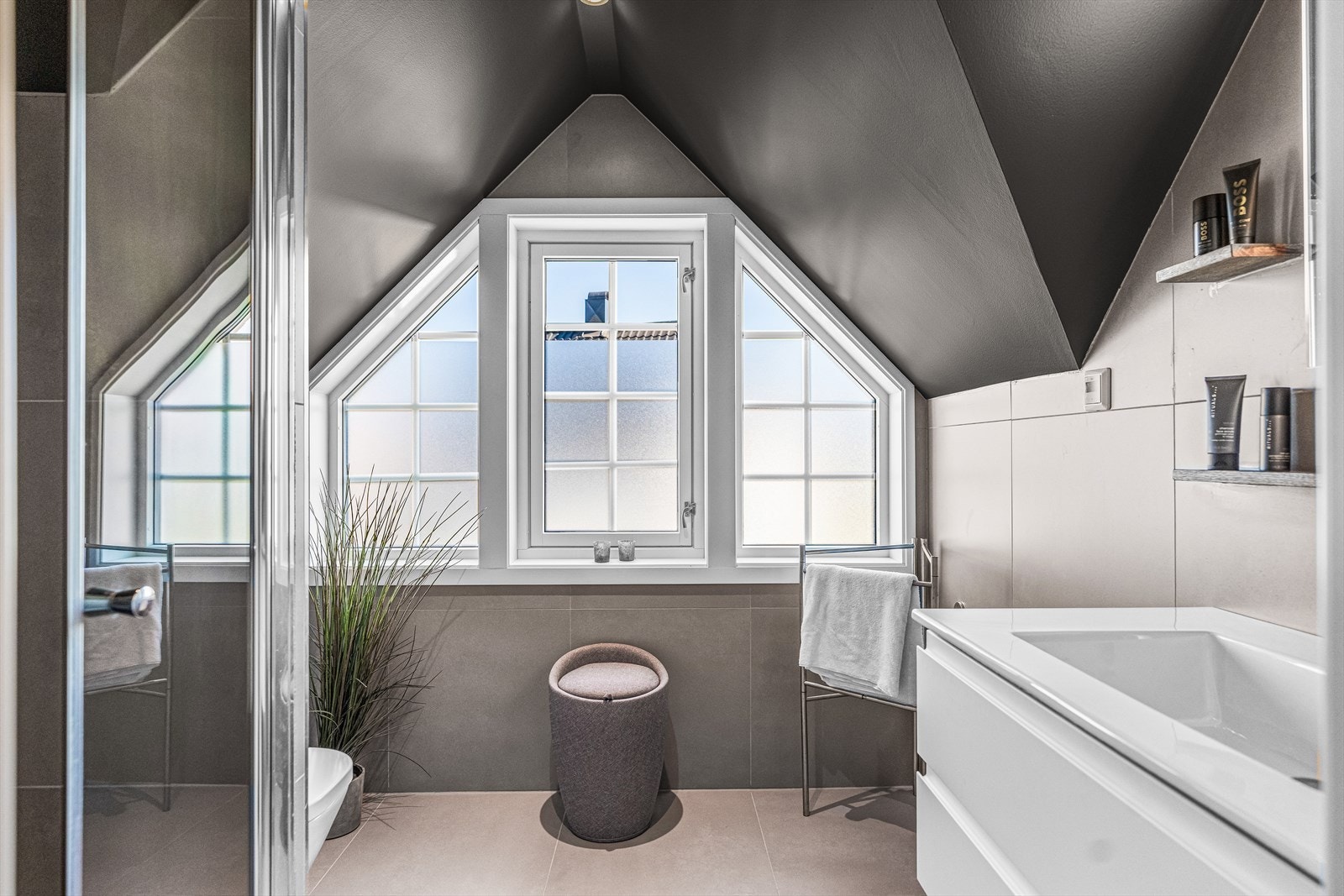 Badet i 2. etasje har store vegg- og gulvfliser i ulike grånyanser. Galleribilde