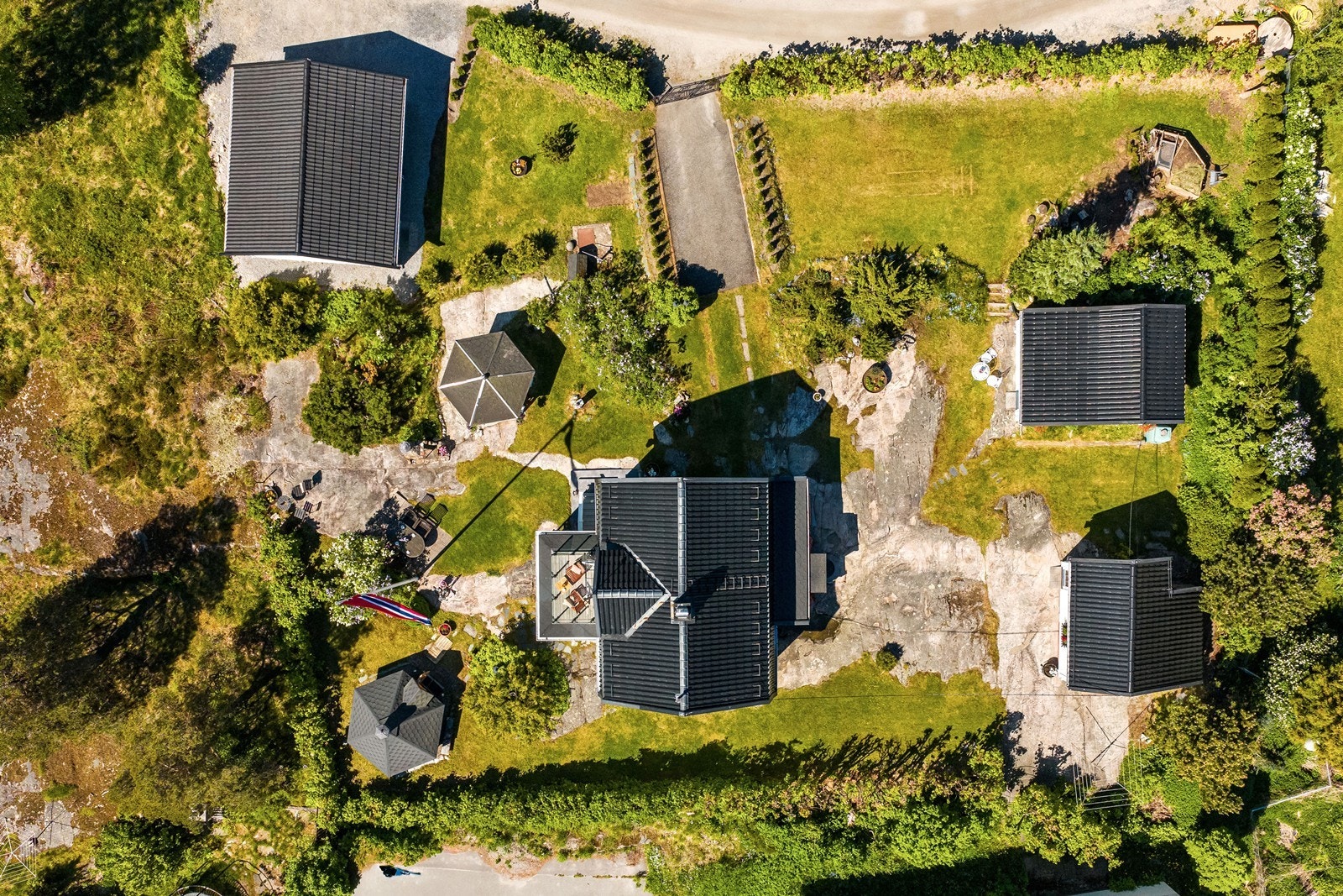 Tomten har variert beplantning med gressplen, trær, hekk, busker og bed, steinlagte partier og naturterreng med flotte svaberg. Galleribilde