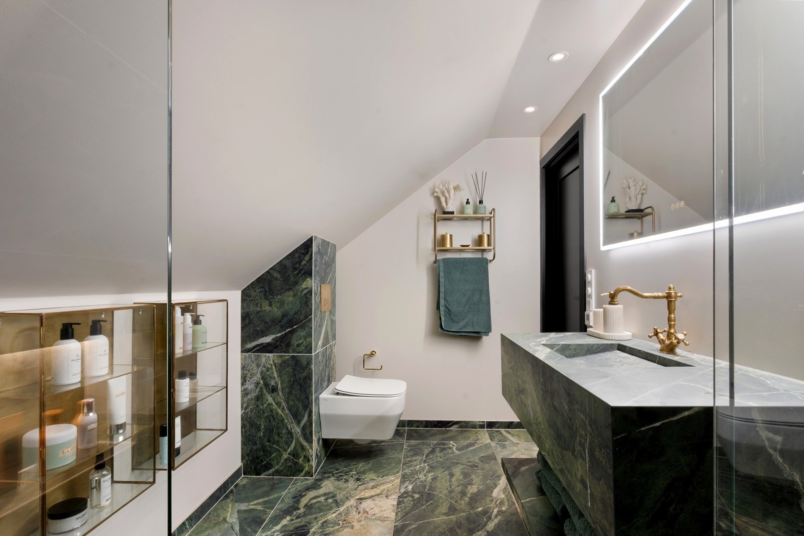 Marmorfliser på gulv, plassbygget servantinnredning og elegant dusjløsning gir badet et eksklusivt uttrykk. Vegghengt toalett og balansert ventilasjon bidrar til både komfort og funksjonalitet. Galleribilde