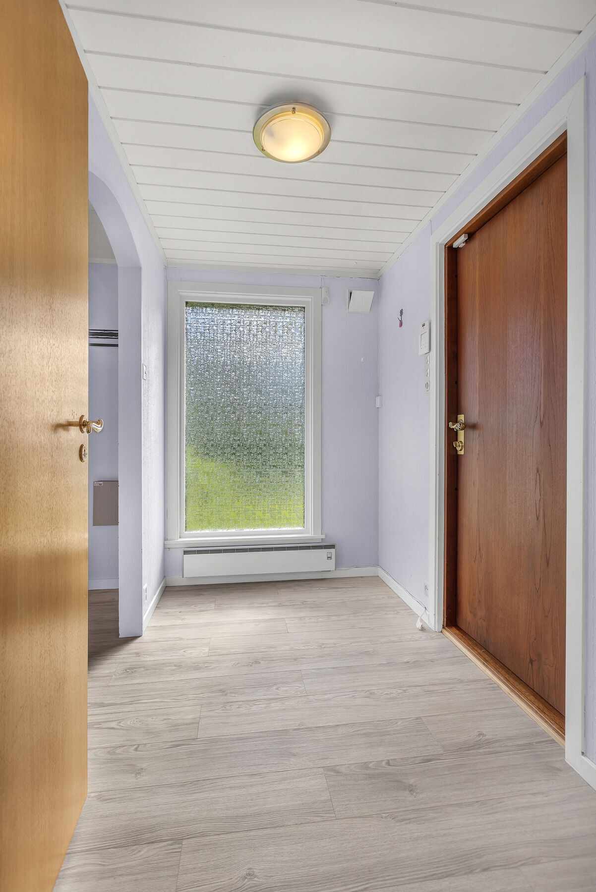Entré med laminat på gulv og adkomst til en praktisk garderobe/bod. Hovedytterdøren er i teak. Galleribilde