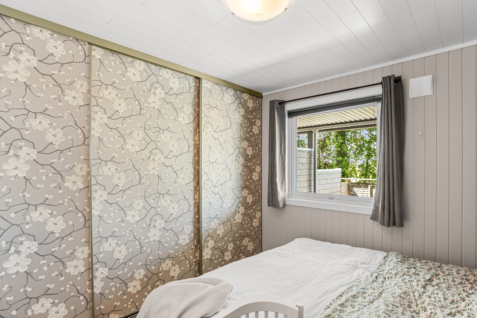 Soverom i underetasjen med laminatgulv og vegger med trepanel og malte plater. Galleribilde
