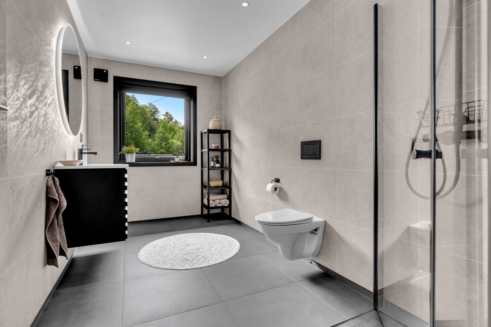 Badet er romslig og lyst med vegghengt toalett og speil med lys over servanten. Galleribilde