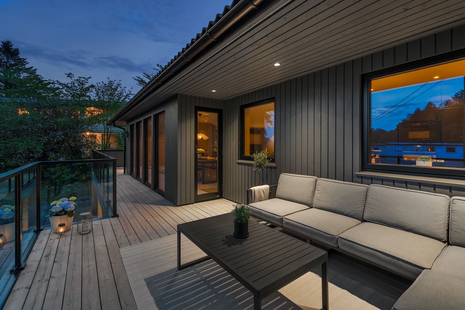 Romslig terrasse med glassrekkverk og delvis overbygd med lys. Galleribilde