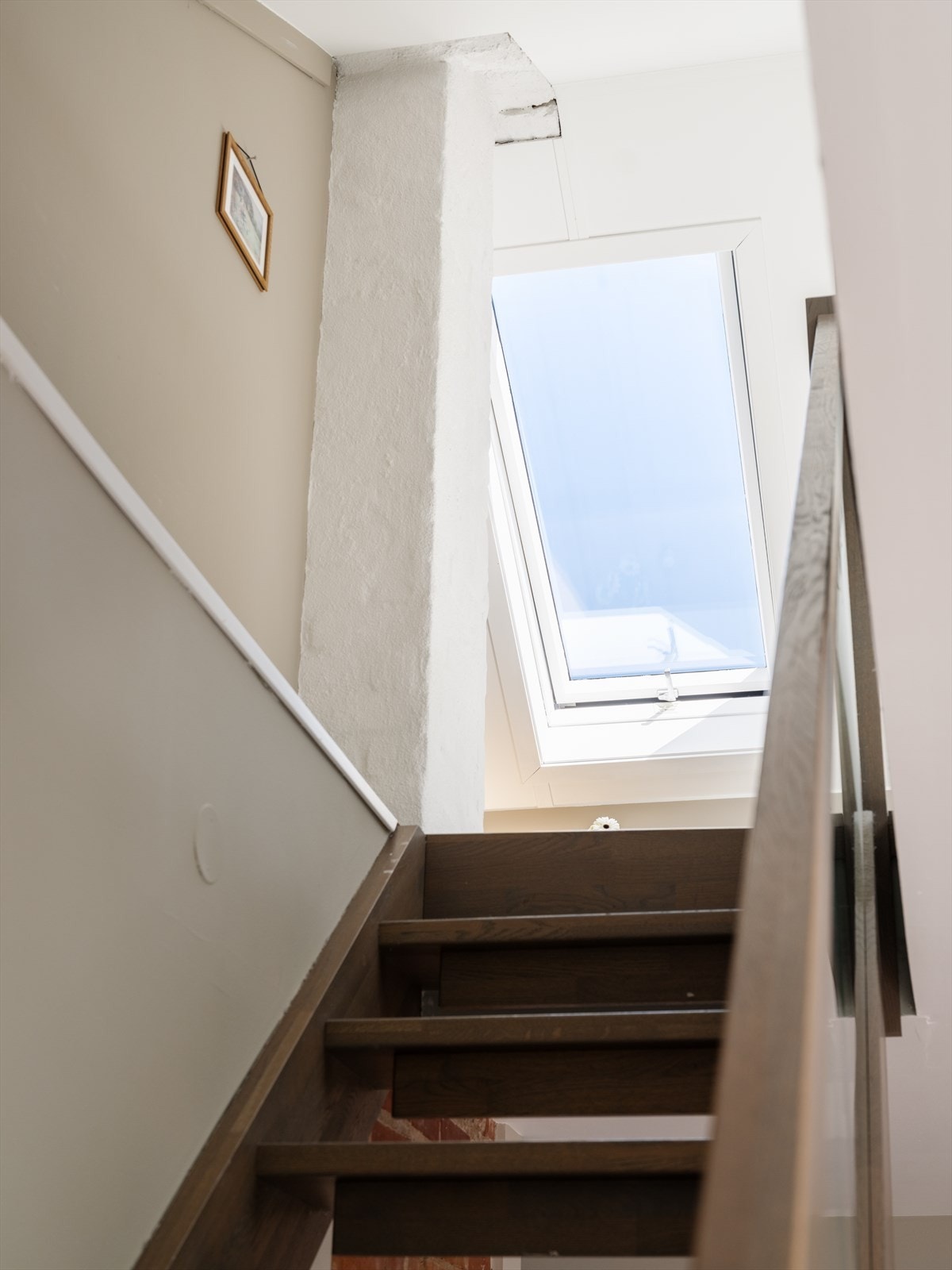 Tretrapp med glassrekkverk leder fra stuen opp til loftsetasjen. Galleribilde