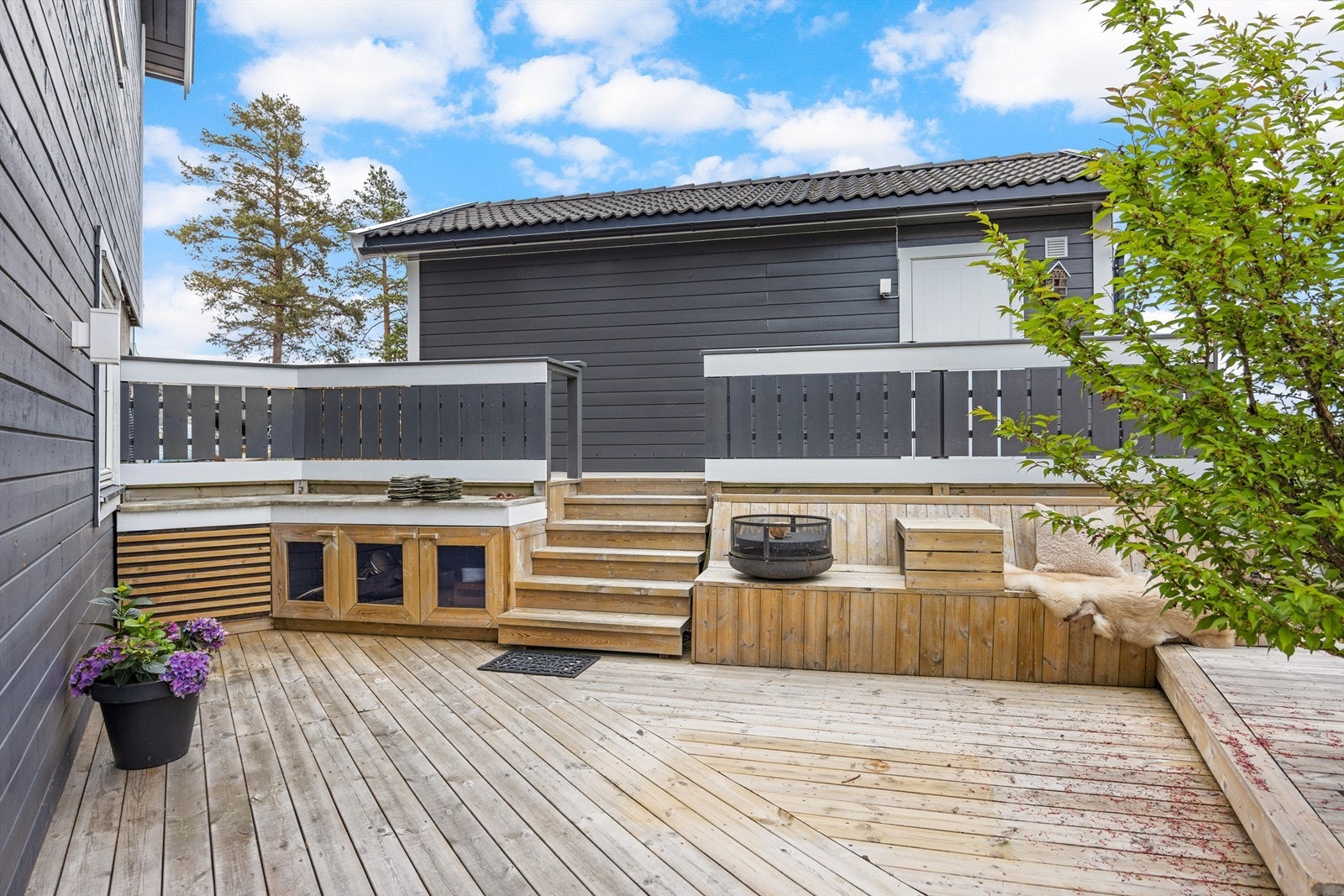 Uteområdet er anlagt med flere nivåer og soner, inkludert en plassbygd sittebenk og bålpanne. Galleribilde