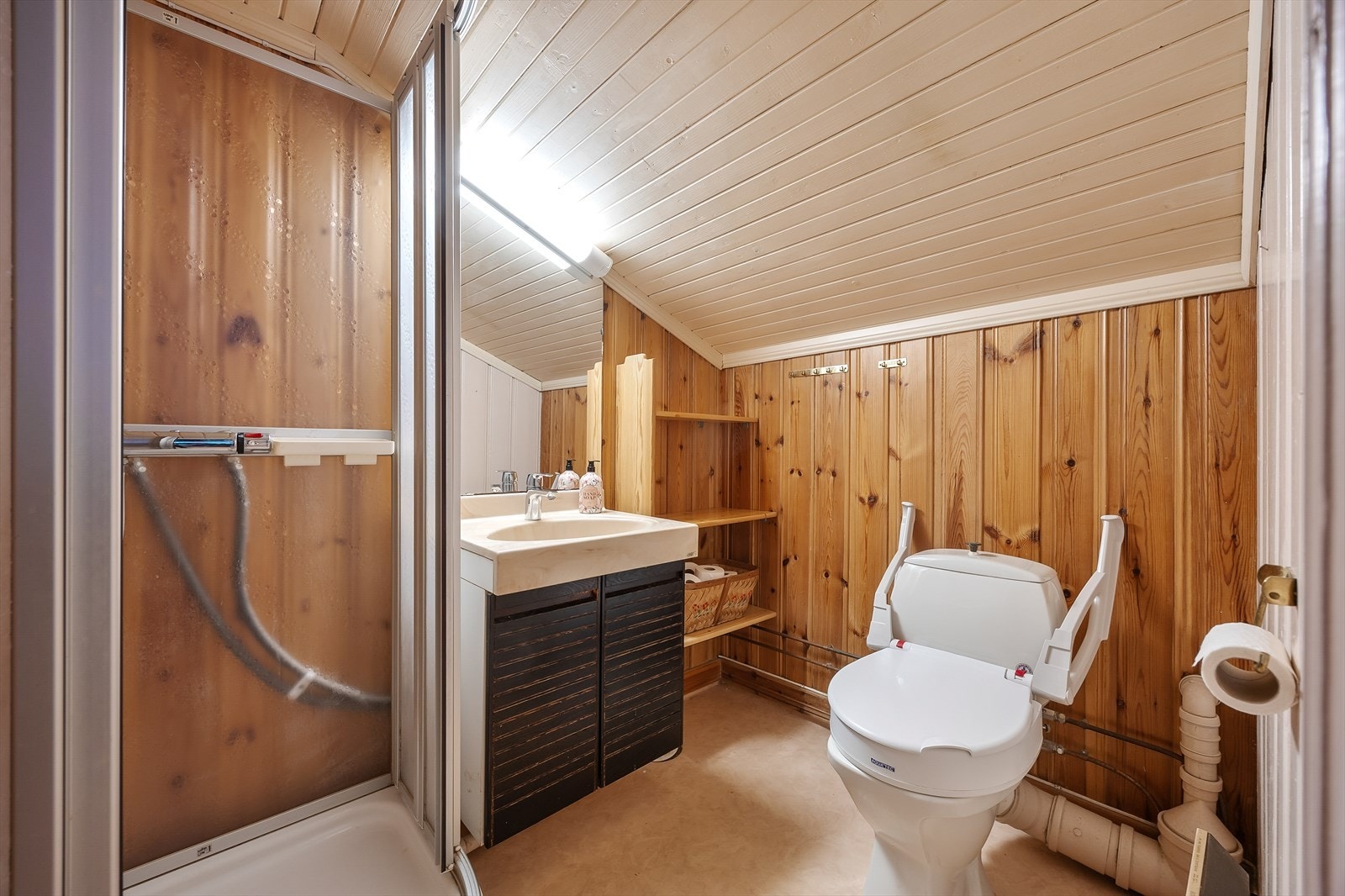 Badet i 2. etasjen er av eldre årgang, med vinylbelegg på gulv, panel på vegger og dusjkabinett. Galleribilde