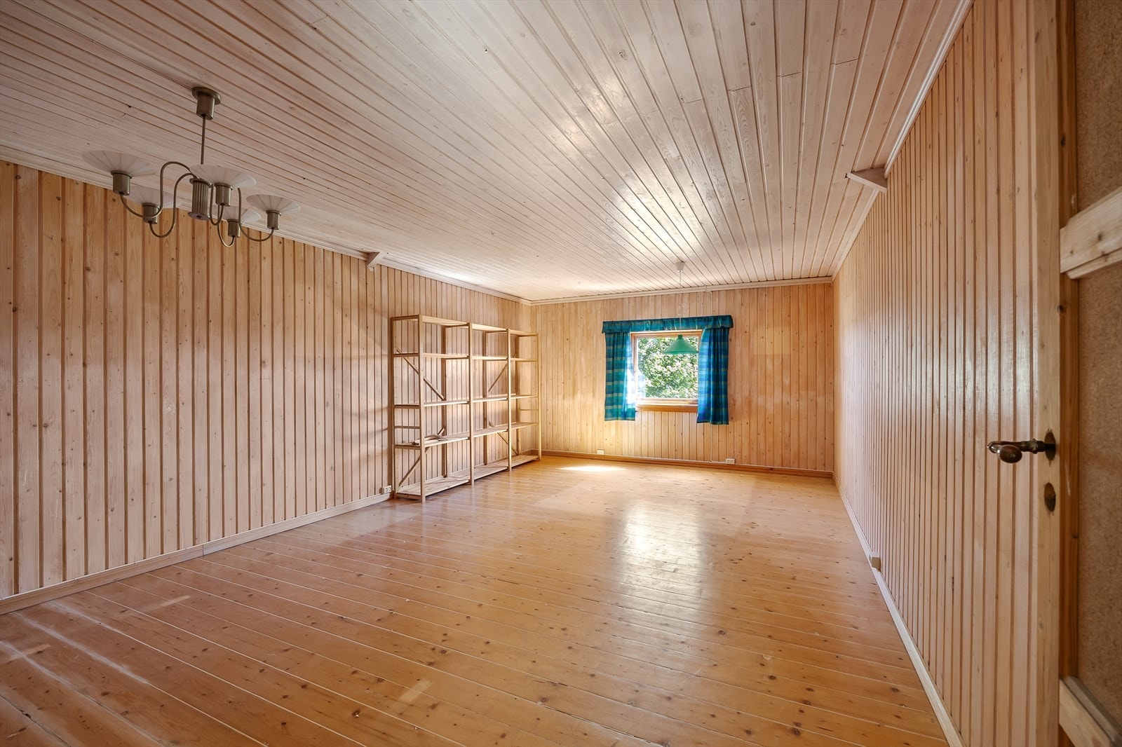 Et uinnredet rom med trepanel og tregulv gir fleksible bruksmuligheter. Galleribilde