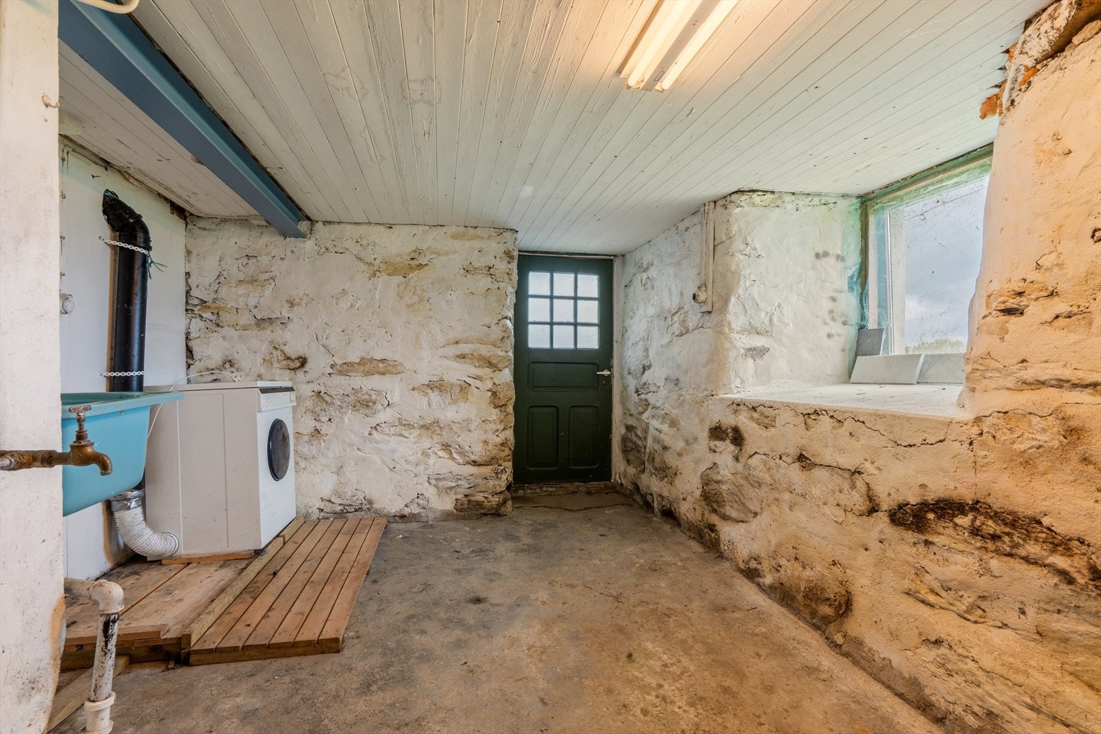 Praktisk vaskekjeller med utslagsvask, opplegg for vaskemaskin og egen utgang. Galleribilde
