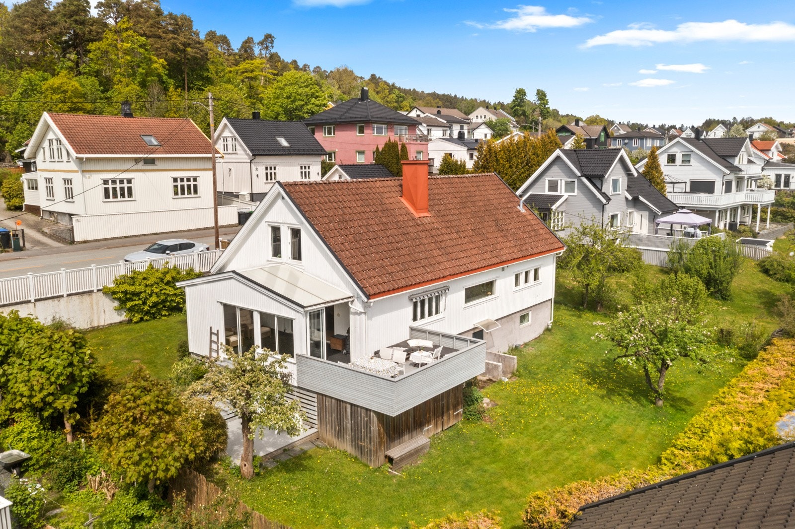 Klassisk enebolig med hvitmalt fasade, tak tekket med takstein og hyggelig terrasse tilknyttet boligen Galleribilde