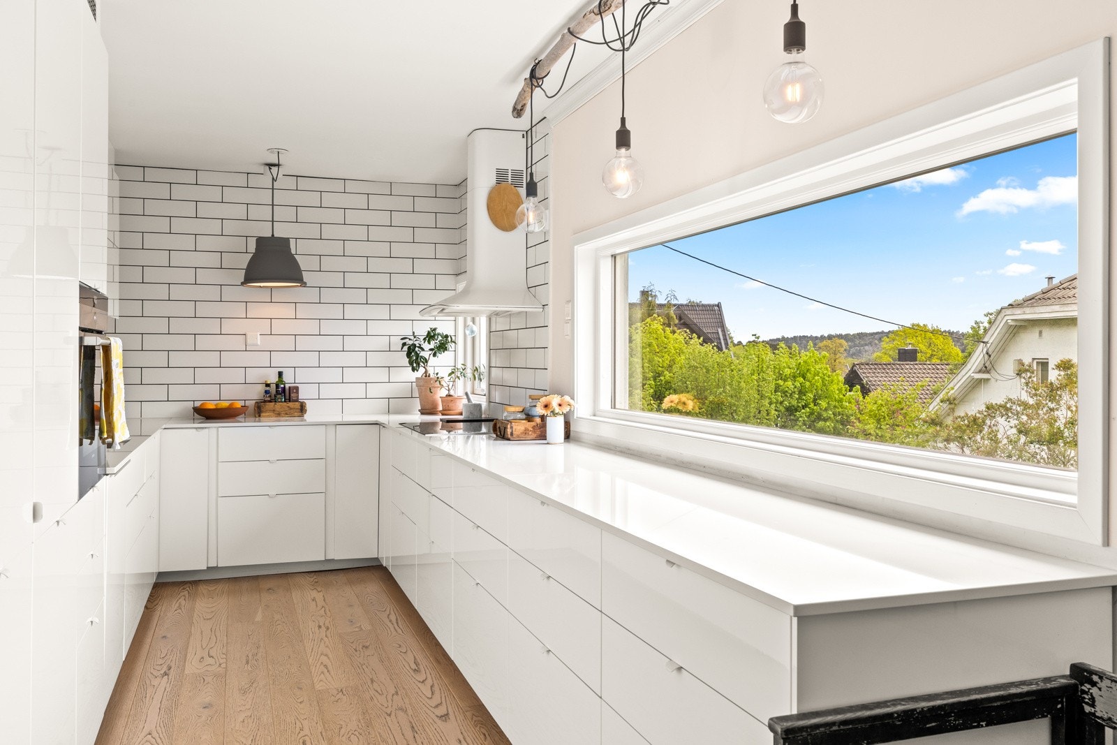 Store vindusflater på kjøkkenet gir rikelig med naturlig lys og hyggelig utsyn mot sjøen og grønne omgivelser. Galleribilde