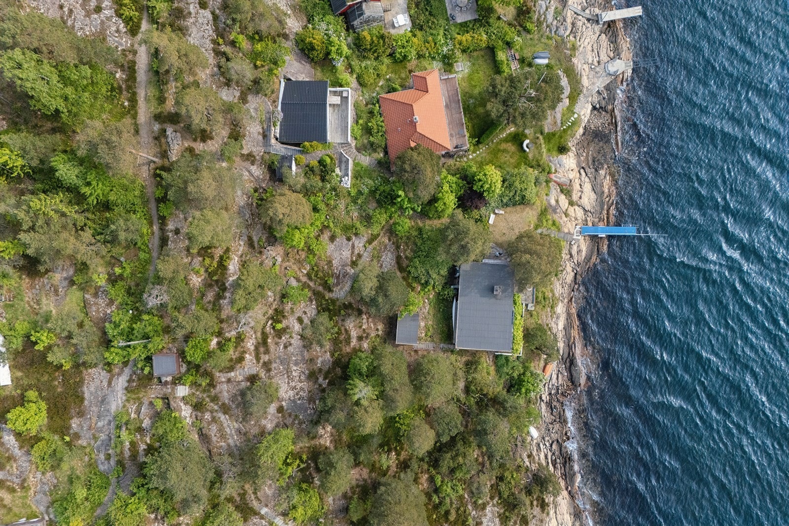 Tomten er fundamentert på fjell, med støpte betongtrapper i terrenget ned mot bryggen. Galleribilde