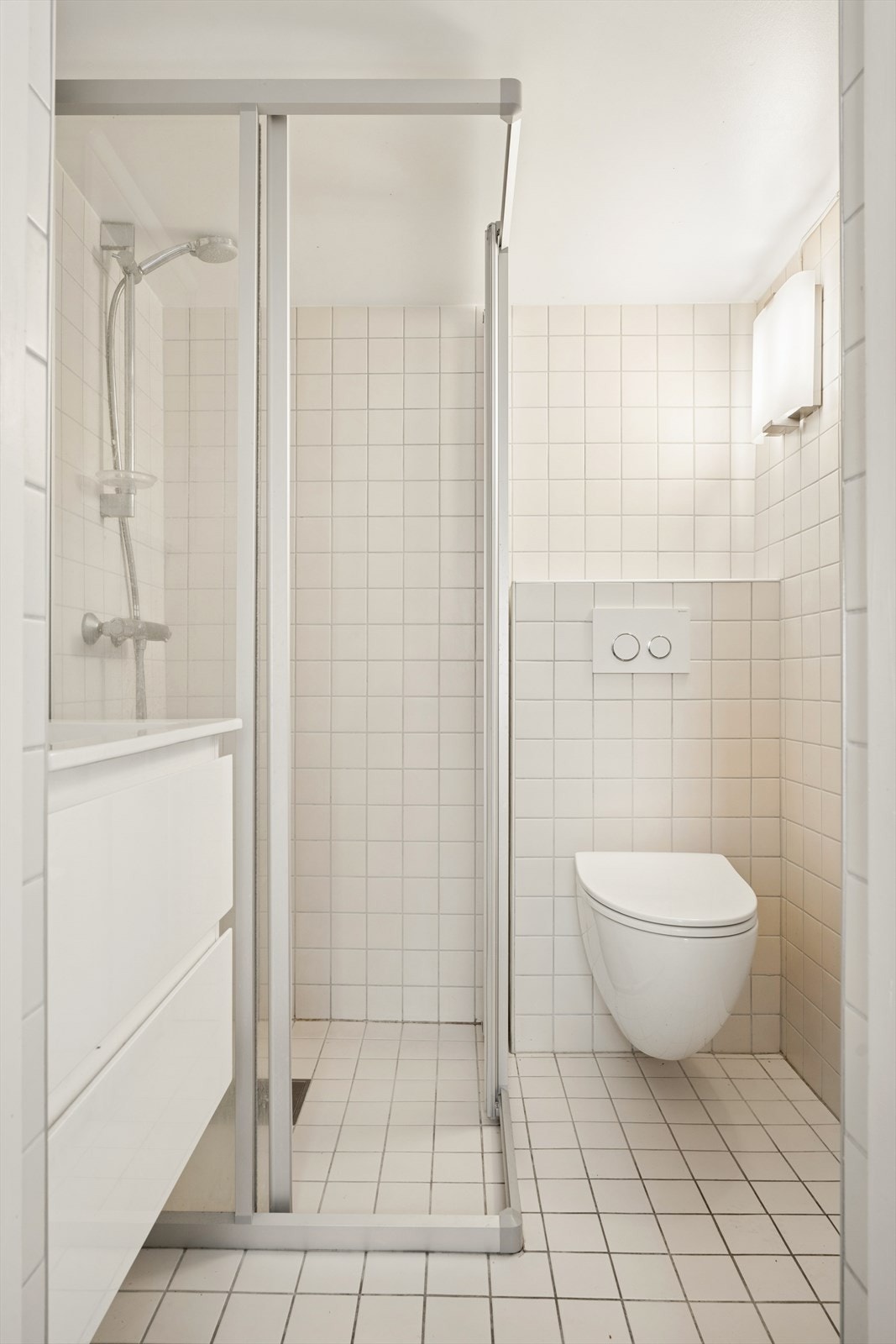 Badet er utstyrt med gulvvarme, dusjhjørne, vegghengt toalett og servantinnredning. Galleribilde