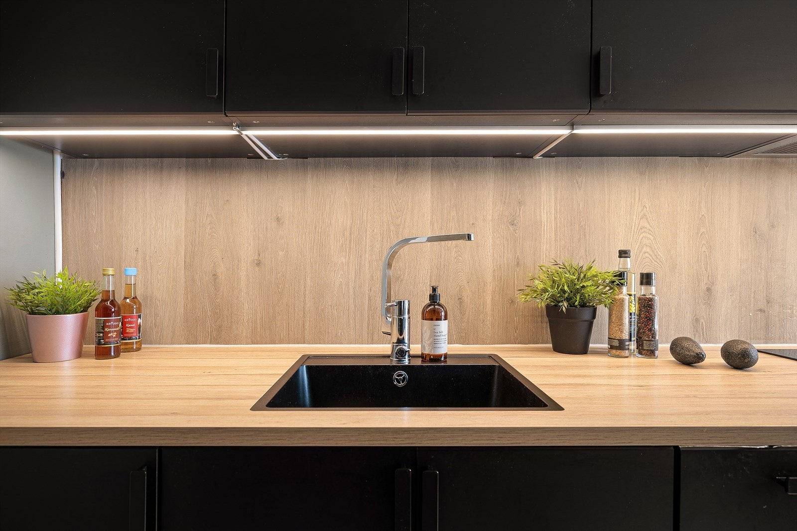 Eksklusiv laminat benkeplate med matchende backsplash og nedfelt vask i mørk stil. Galleribilde