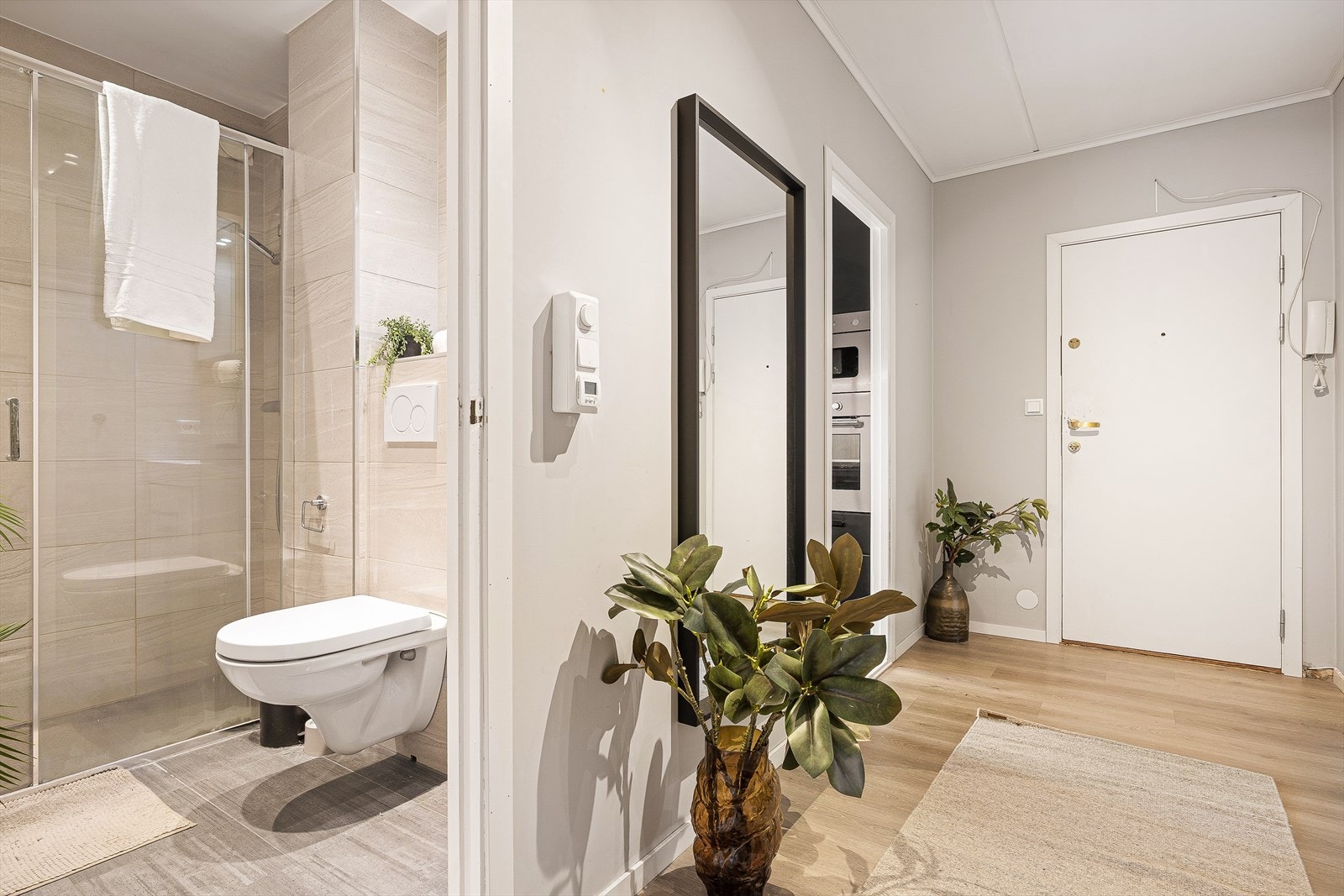 Adkomst til boligens baderom fra entré. Badet ble nytt i 2019 og holder høy standard med et eksklusivt preg, her med vegghengt toalett og romslig dusjsone. Galleribilde