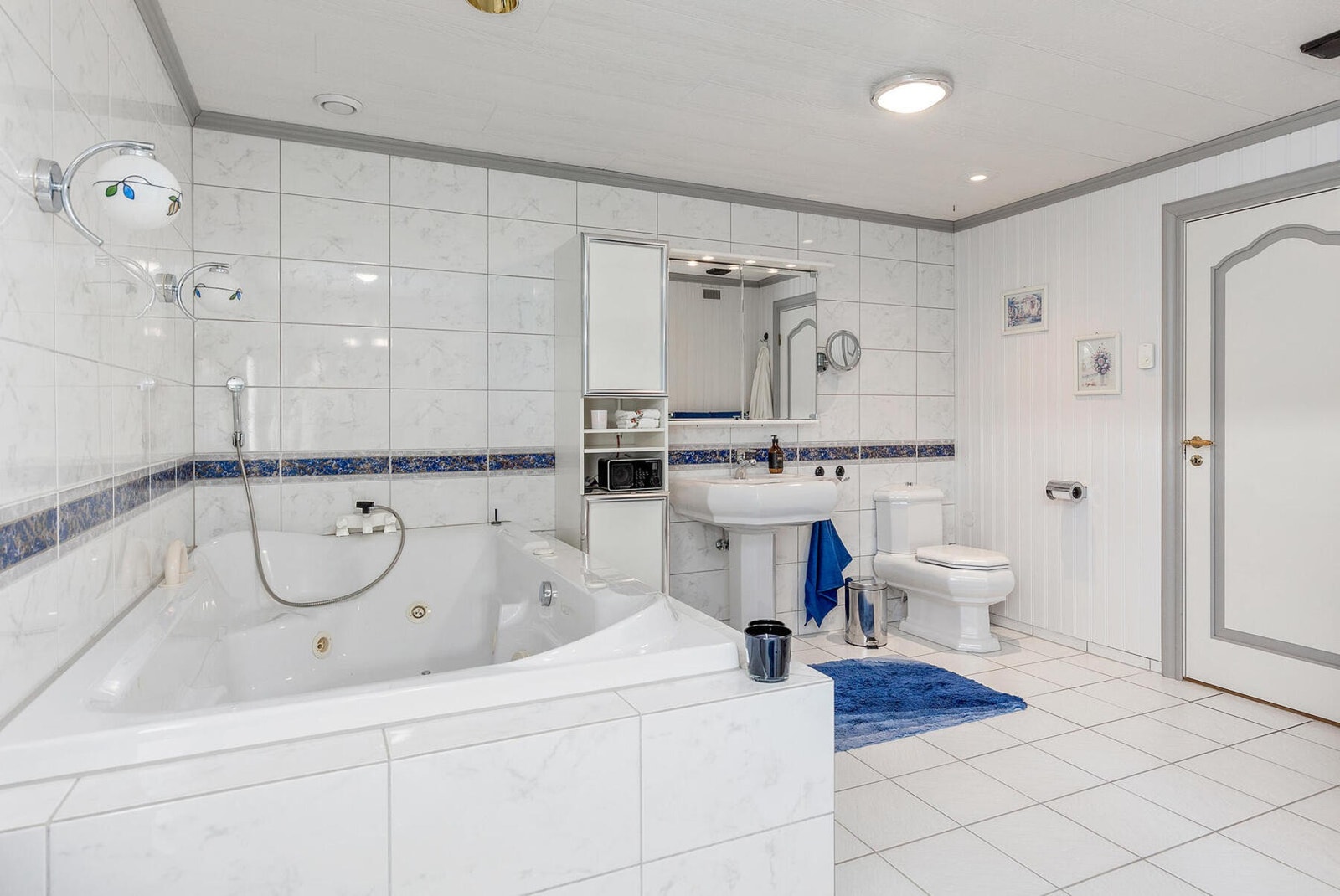 Pent flislagt bad med wc, servant, badekar, bidé, servantskap, mekanisk avtrekk og dusjhjørne. Galleribilde