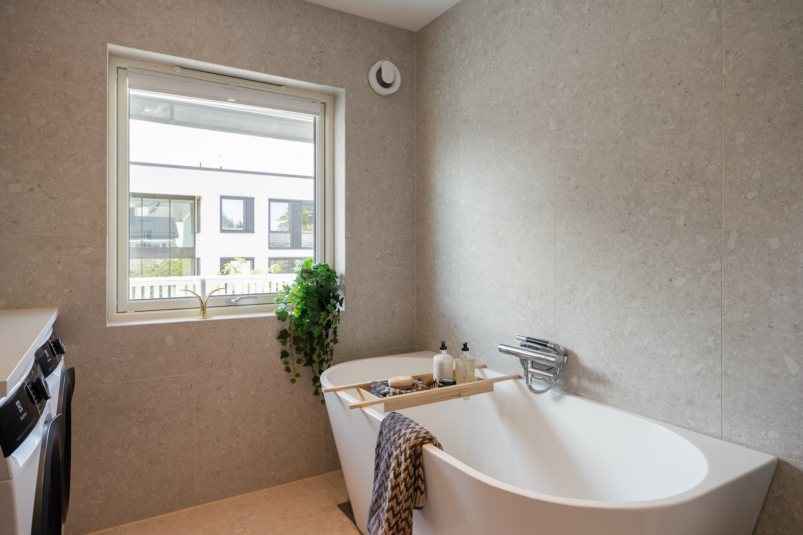 Videre er badet utstyrt med badekar, opplegg for vaskemaskin, mekanisk avtrekk, servant, servantskap og veggmontert wc. Galleribilde