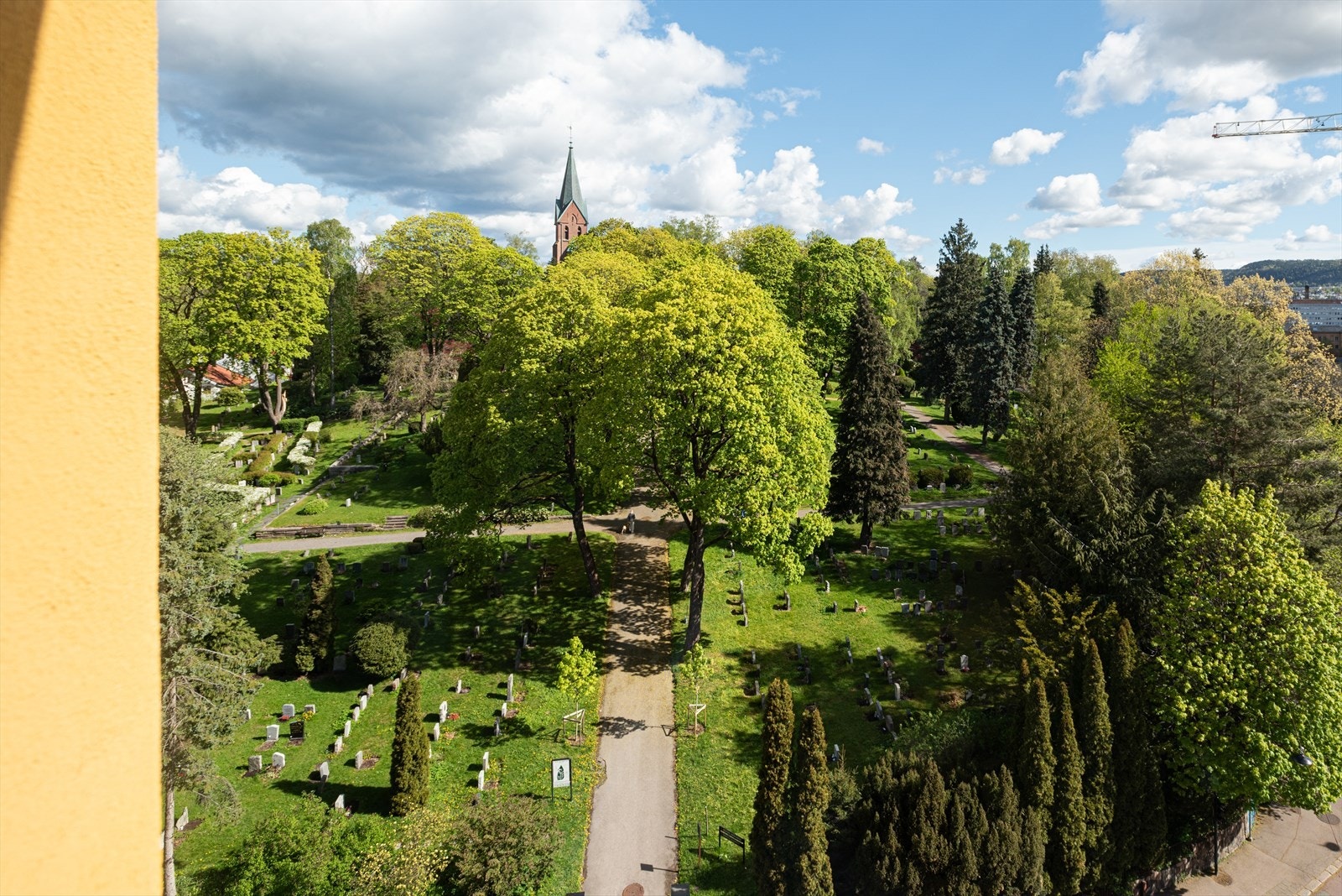 Vestre Aker kirke ligger på andre siden av gaten - grønn og frodig utsikt fra balkongen. Om høsten blir kirkegården knallrød når alle lønnetrærne ikler seg høstfarger. Galleribilde