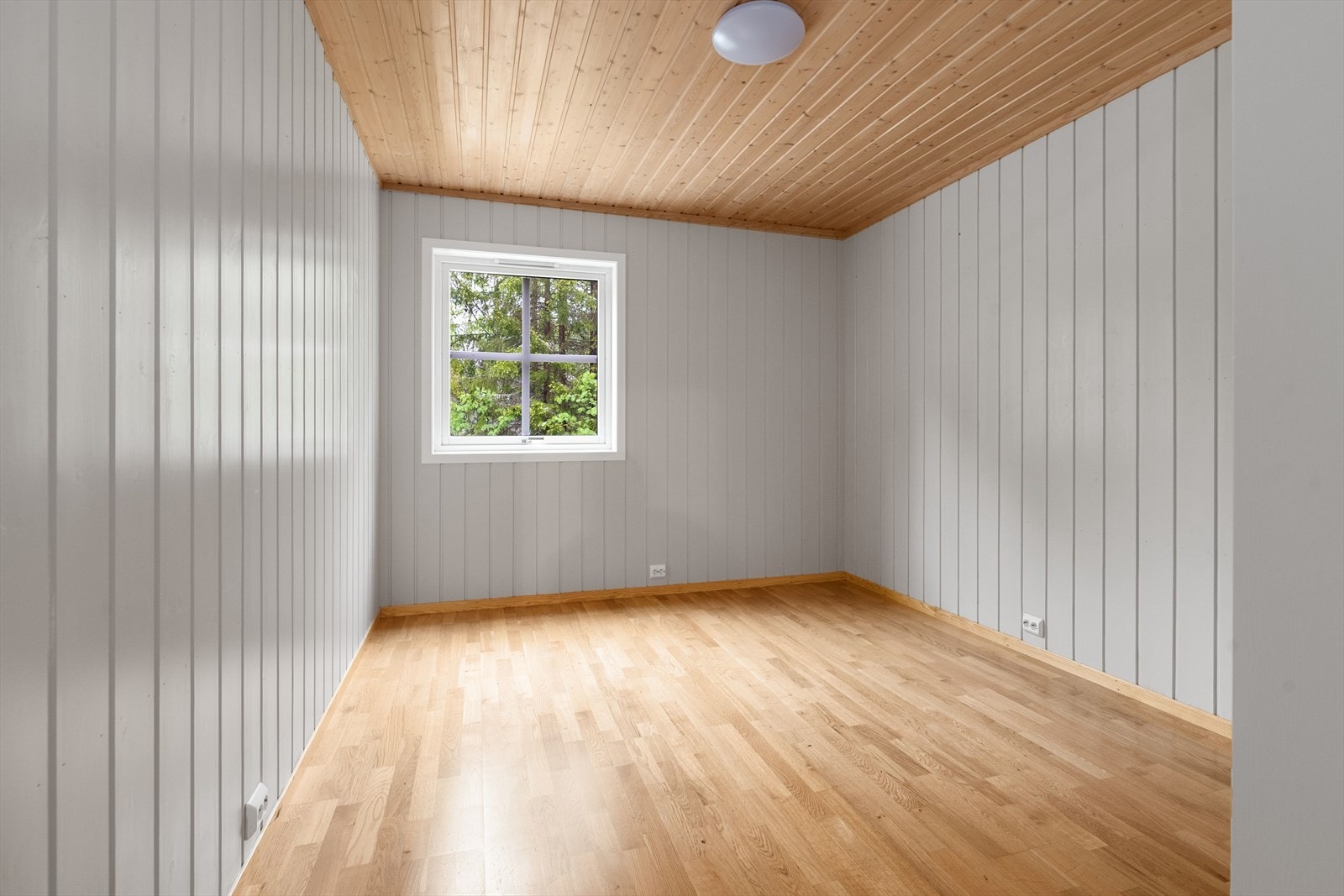 Soverom i første etasje med parkett på gulvet og panel på vegger og i tak. Galleribilde