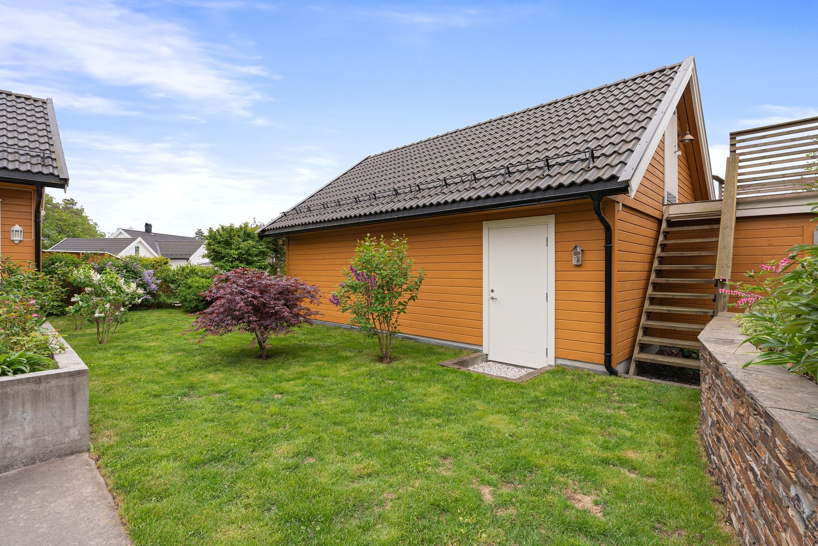 Det er en ekstra inngang til garasjen fra hagen, trapp opp til en ekstra terrasse og inngang til garasjeloftsbod. Galleribilde