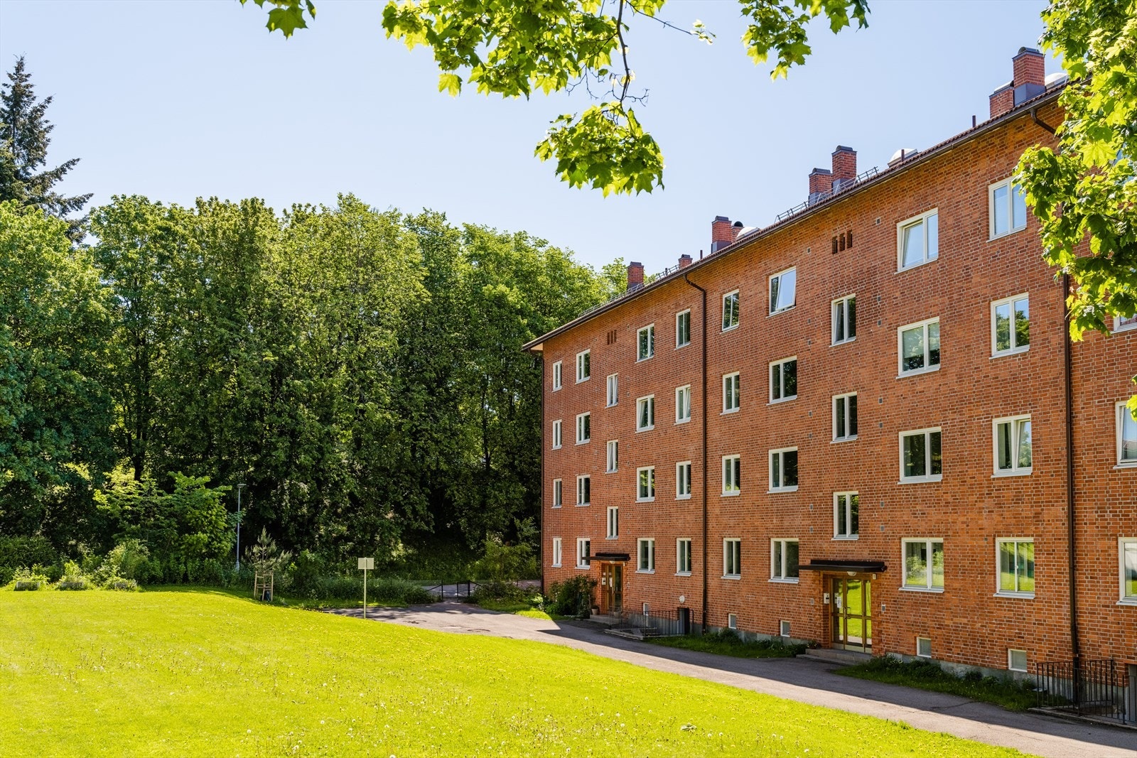 Baksiden av bygården, der inngangspartiet og ringeklokken befinner seg. Store grøntområder omkranser bygningen. Galleribilde