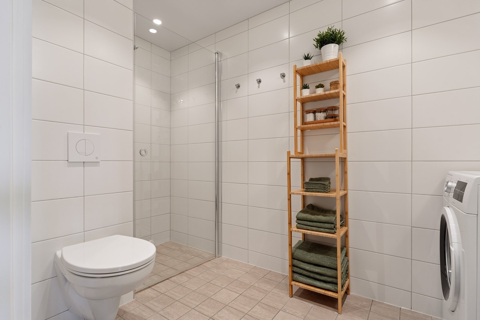 Badet er innredet med vegghengt toalett og dusjhjørne med innfellbare glassdører. Galleribilde