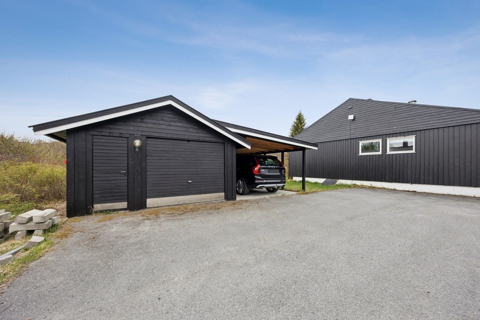 Eiendommen har en romslig garasje med tilhørende carport, som gir rikelig med plass til parkering og lagring. Galleribilde