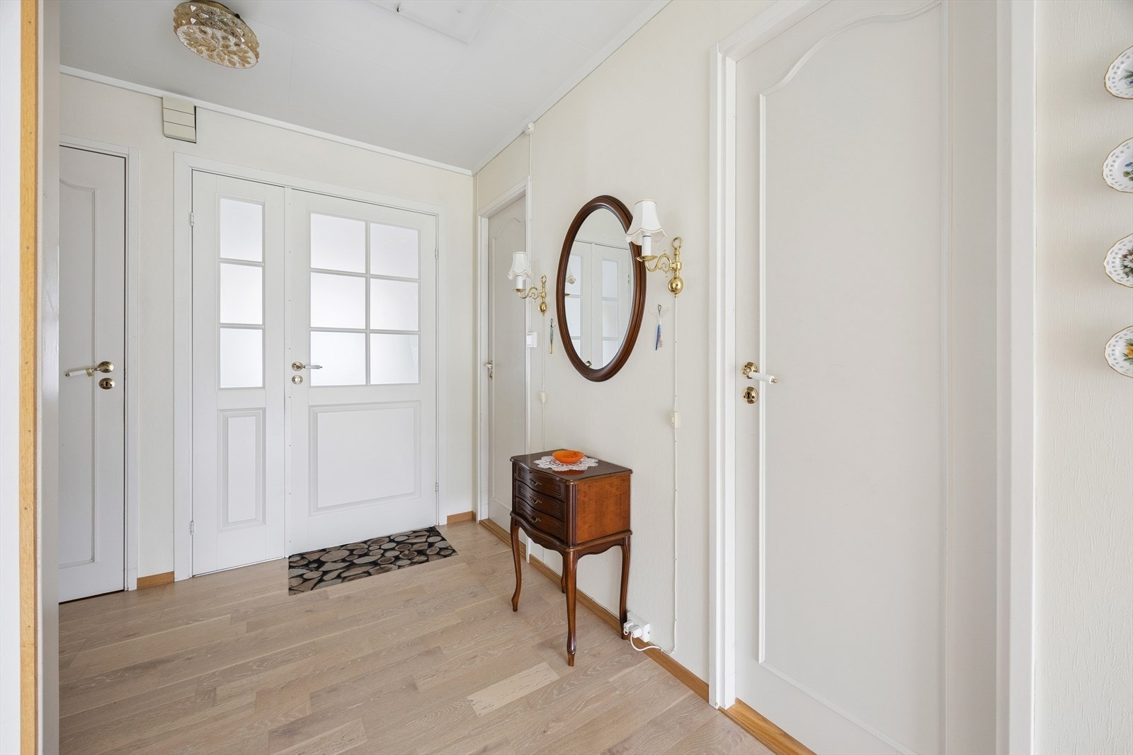 Entré med malte fyllingsdører som fører videre inn i boligen. Galleribilde