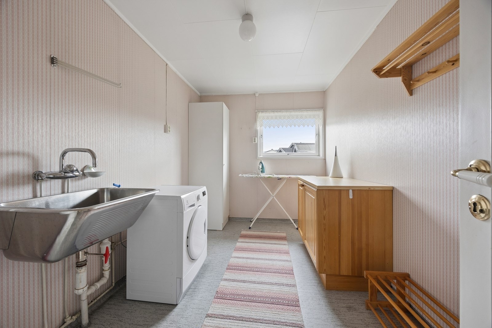 Eget vaskerom med belegg på gulv, utslagsvask og opplegg for vaskemaskin. Galleribilde